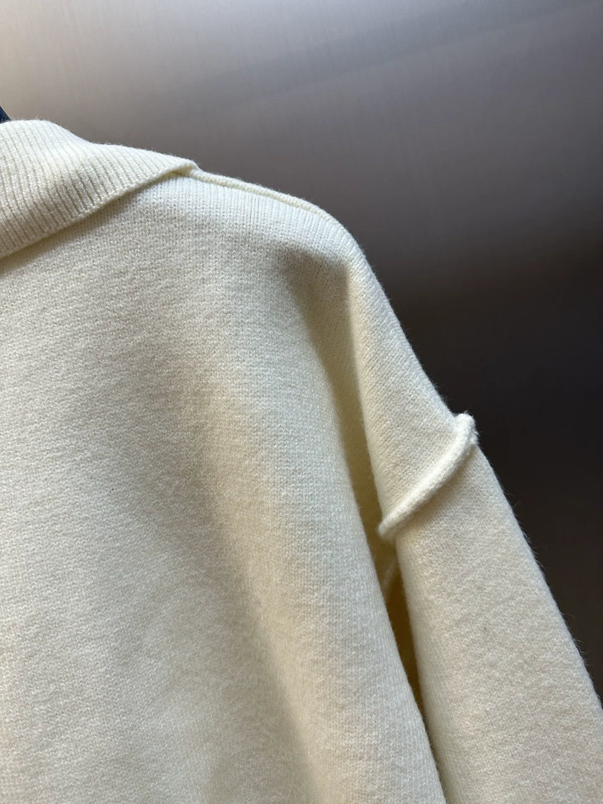 Off-white sweater sleeve and shoulder knit texture, no visible logo in frame
