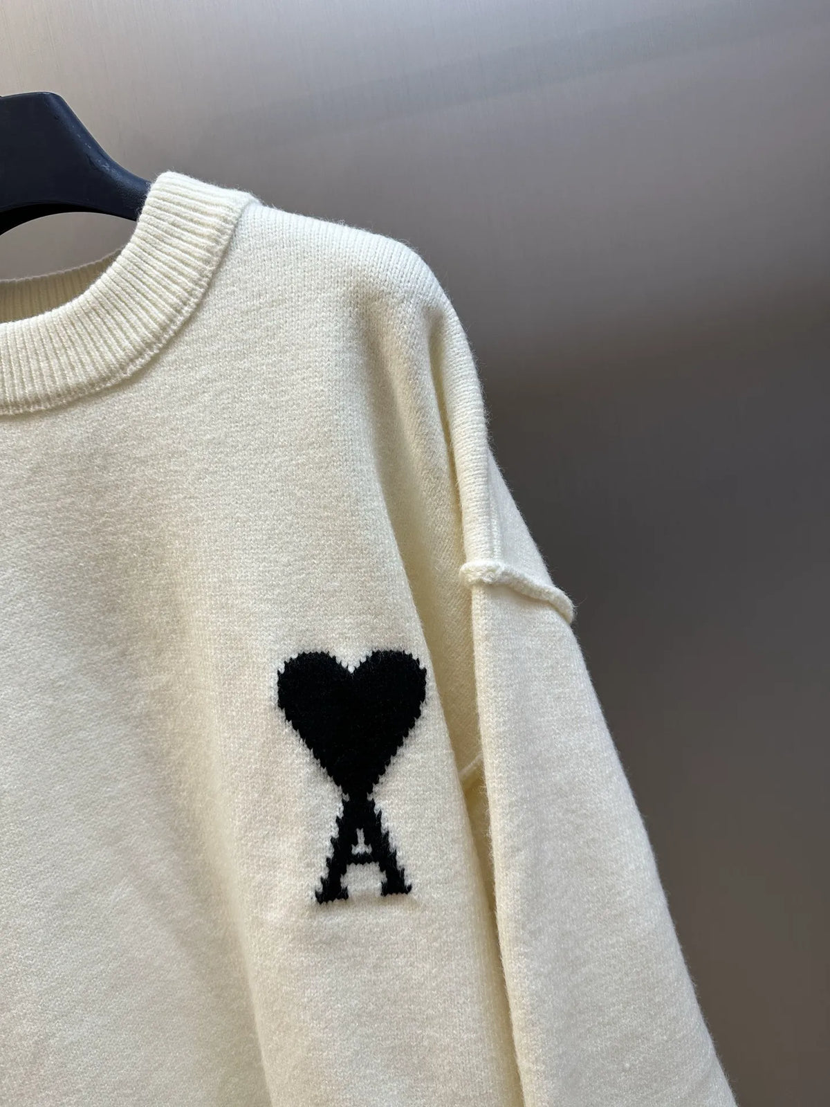 Amiri cream knit sweater sleeve detail with black heart and A patch