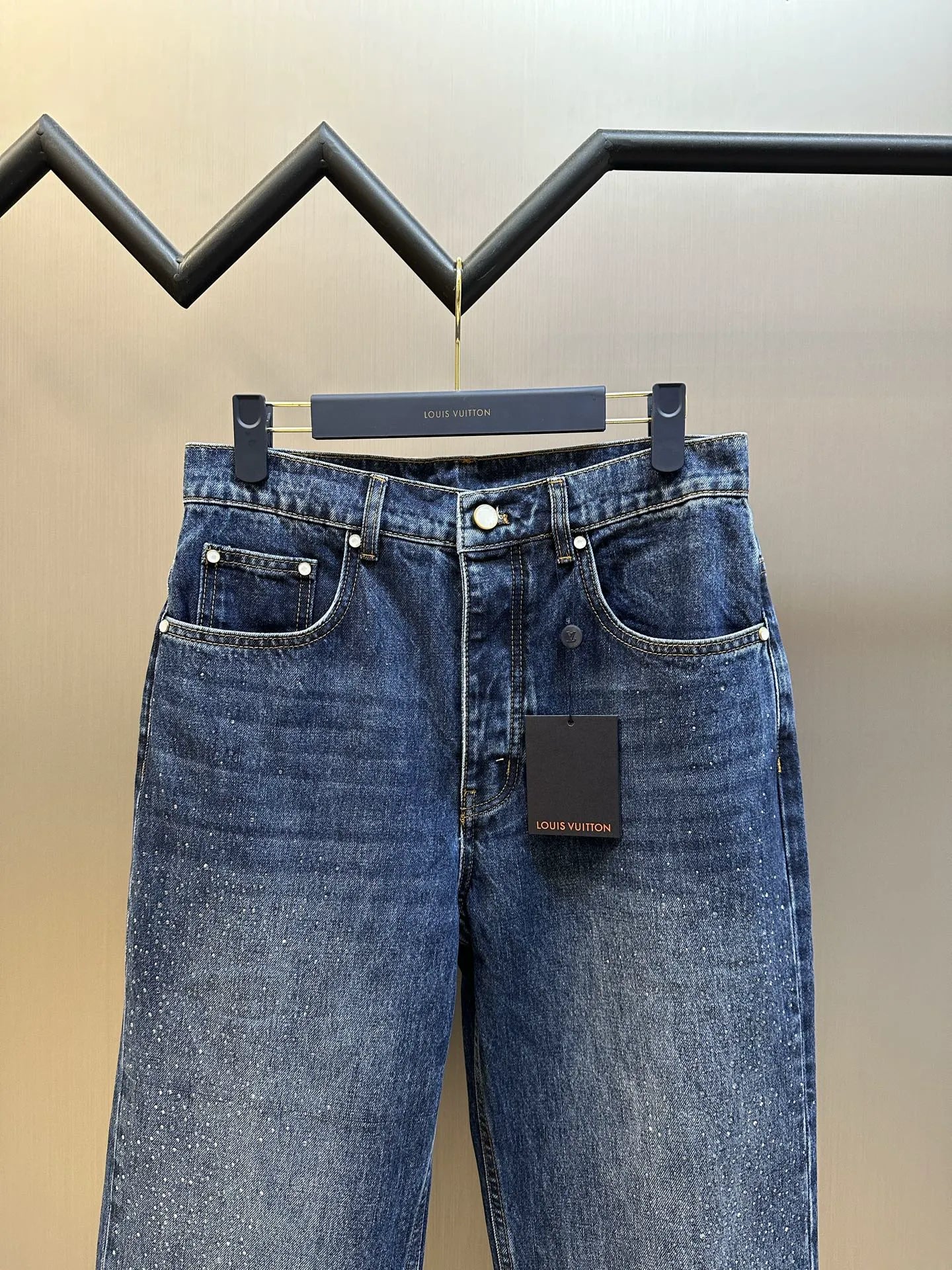 Dark blue denim jeans, back view with patch pockets and button waistband.