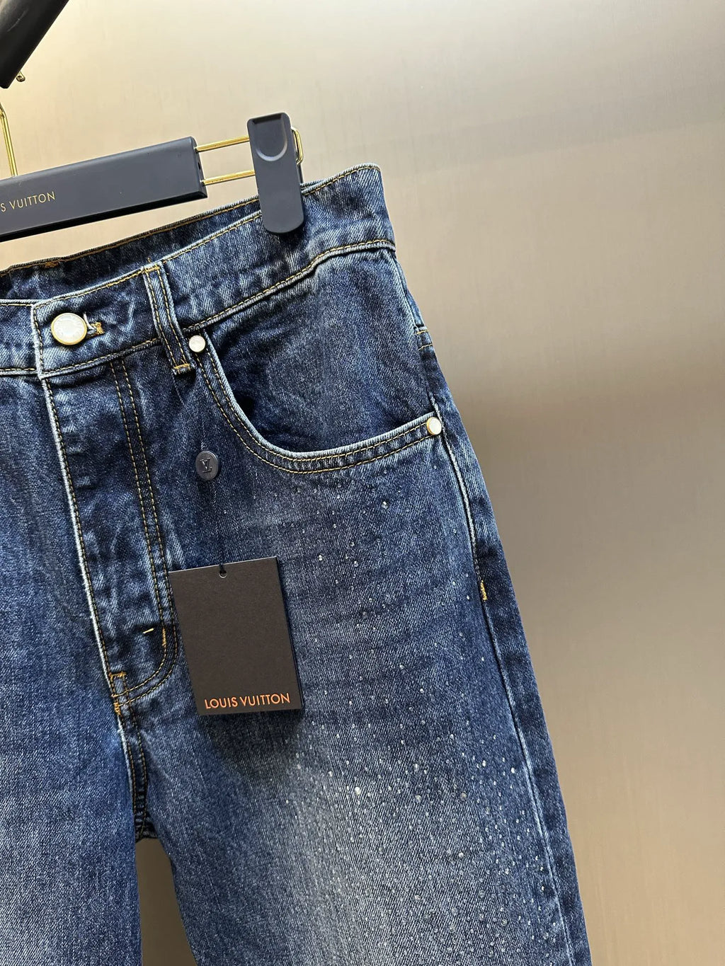 Dark blue denim jeans with curved pocket stitching and visible Louis Vuitton label.