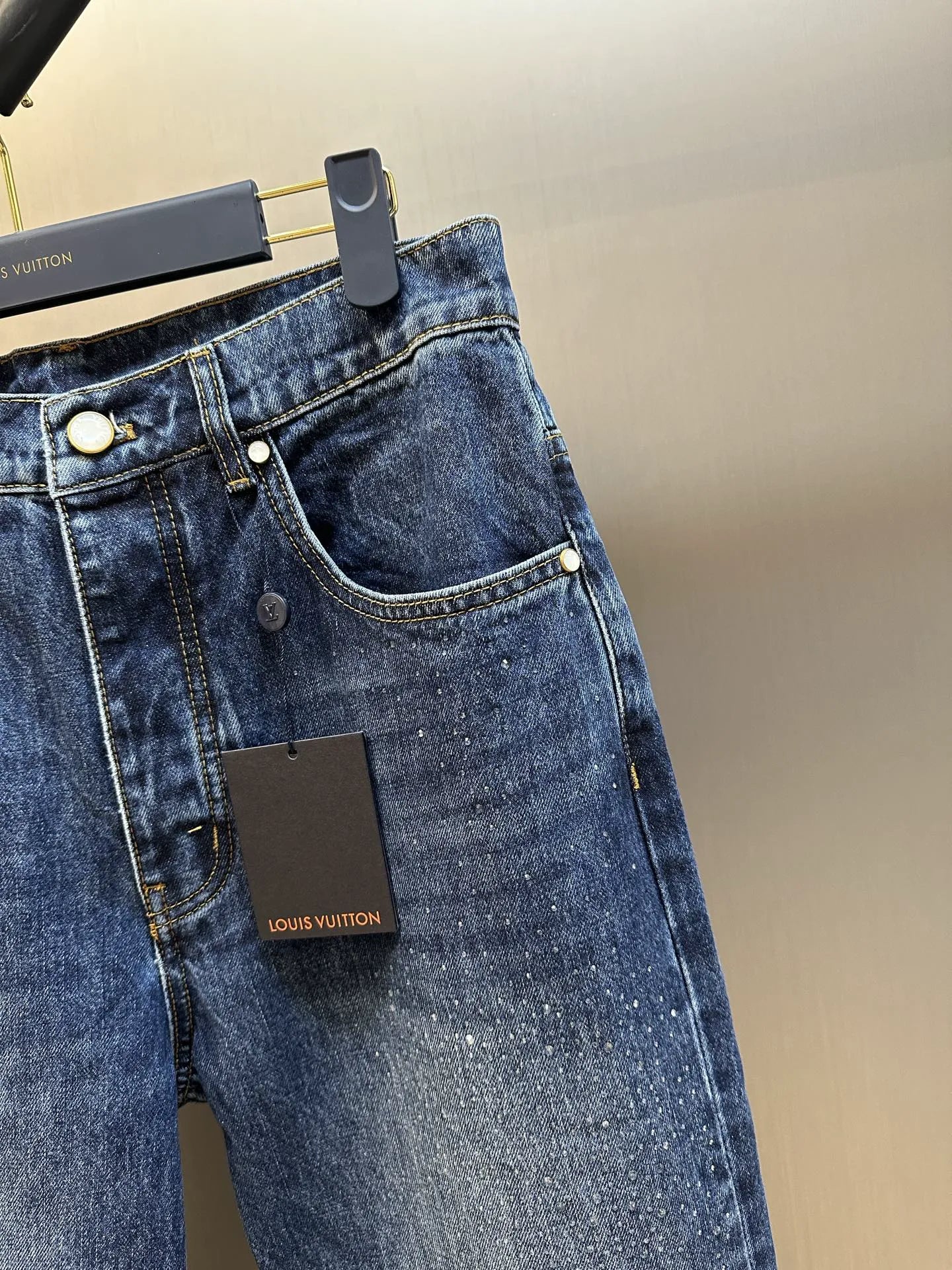 Dark blue denim jeans with curved pocket stitching and visible Louis Vuitton label.