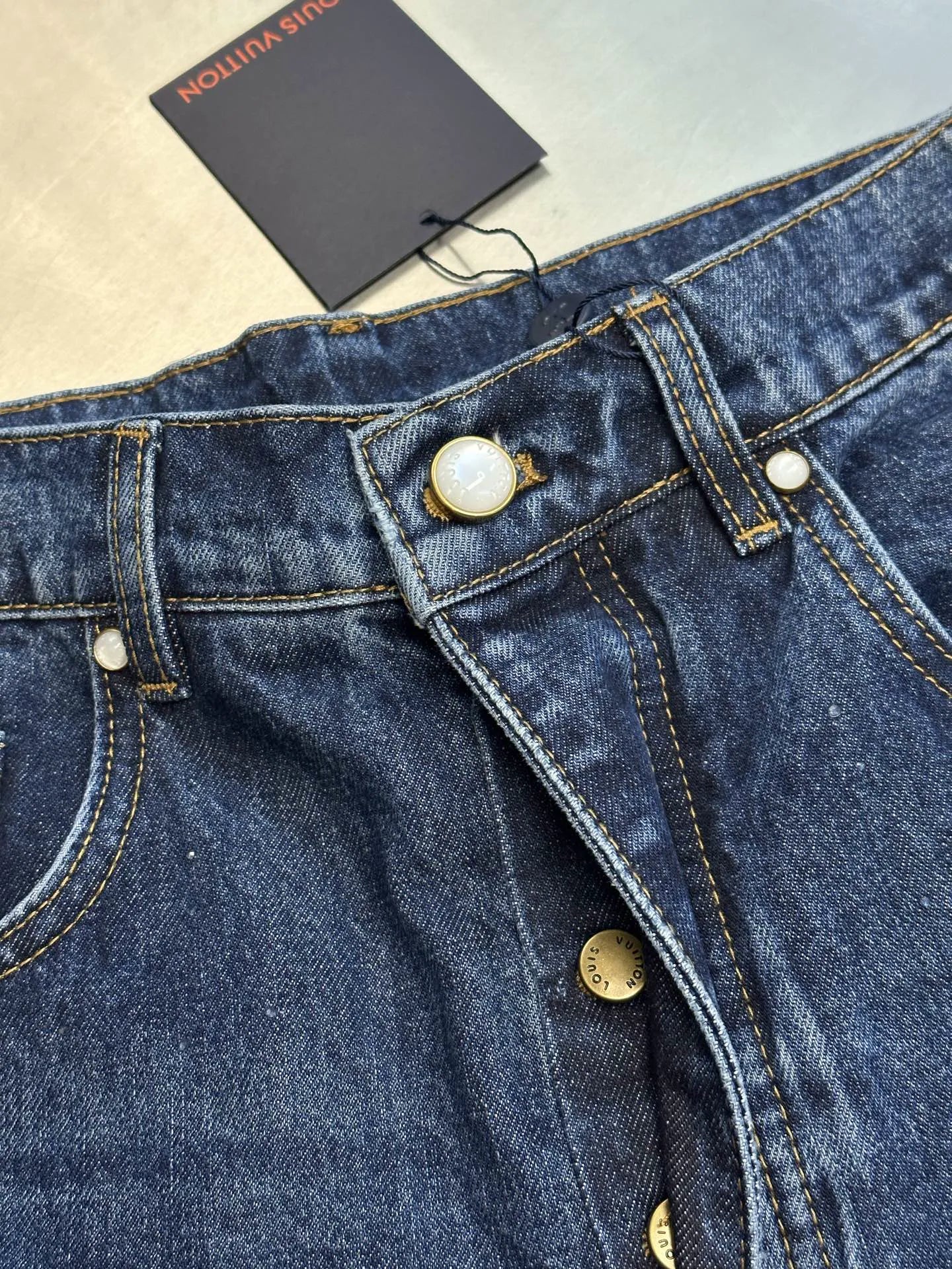 Dark blue denim jeans waistband close-up with buttoned fly and belt loops.