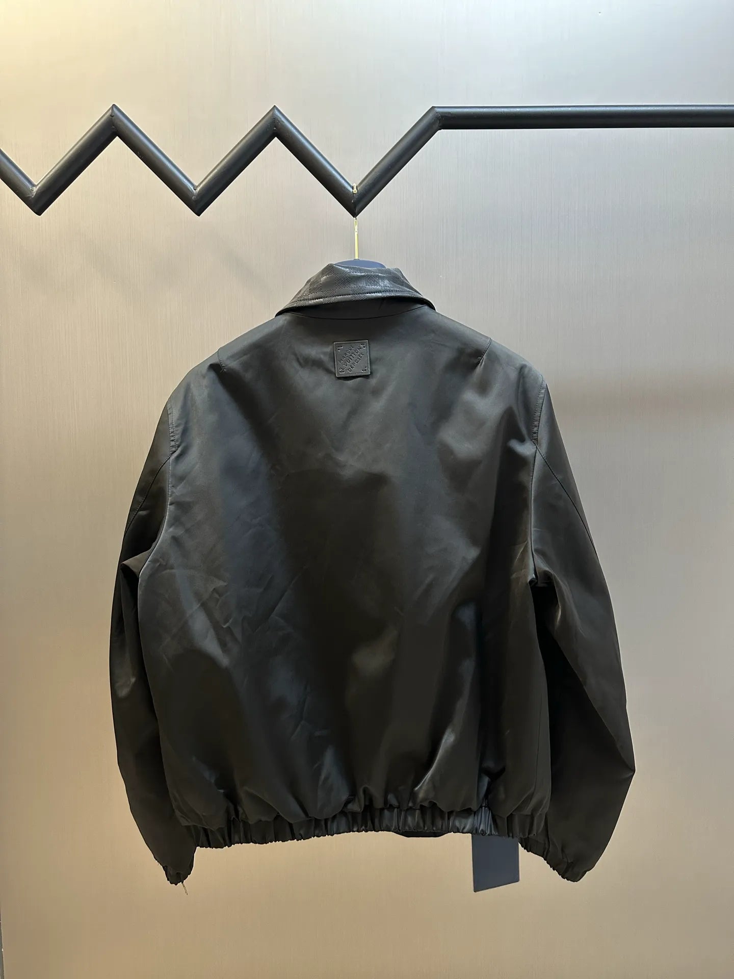 Dark monogram zip-up jacket back view with ribbed hem and elastic cuffs