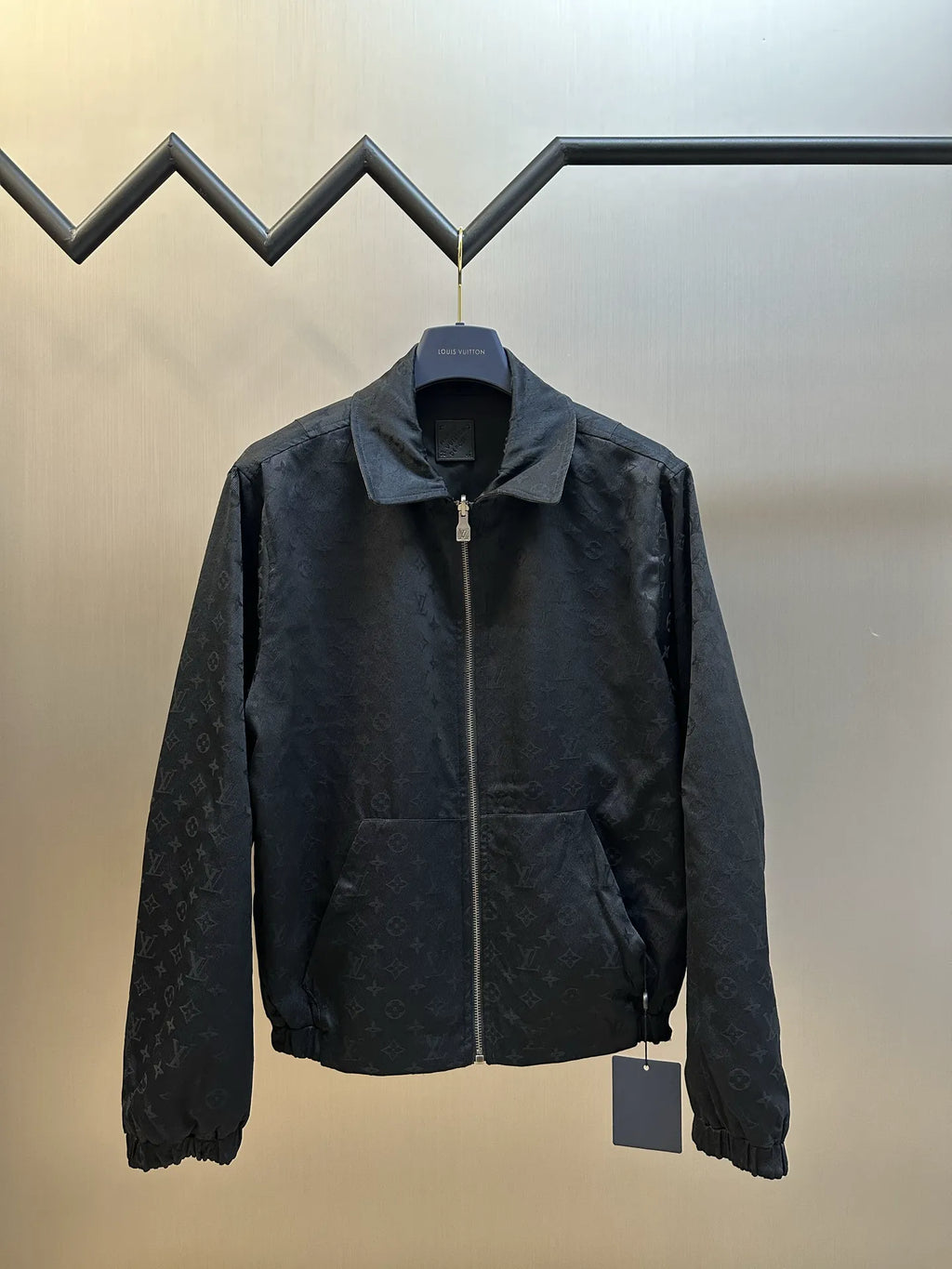 Dark monogram zip-up jacket with stand collar, chest logo, and zip front