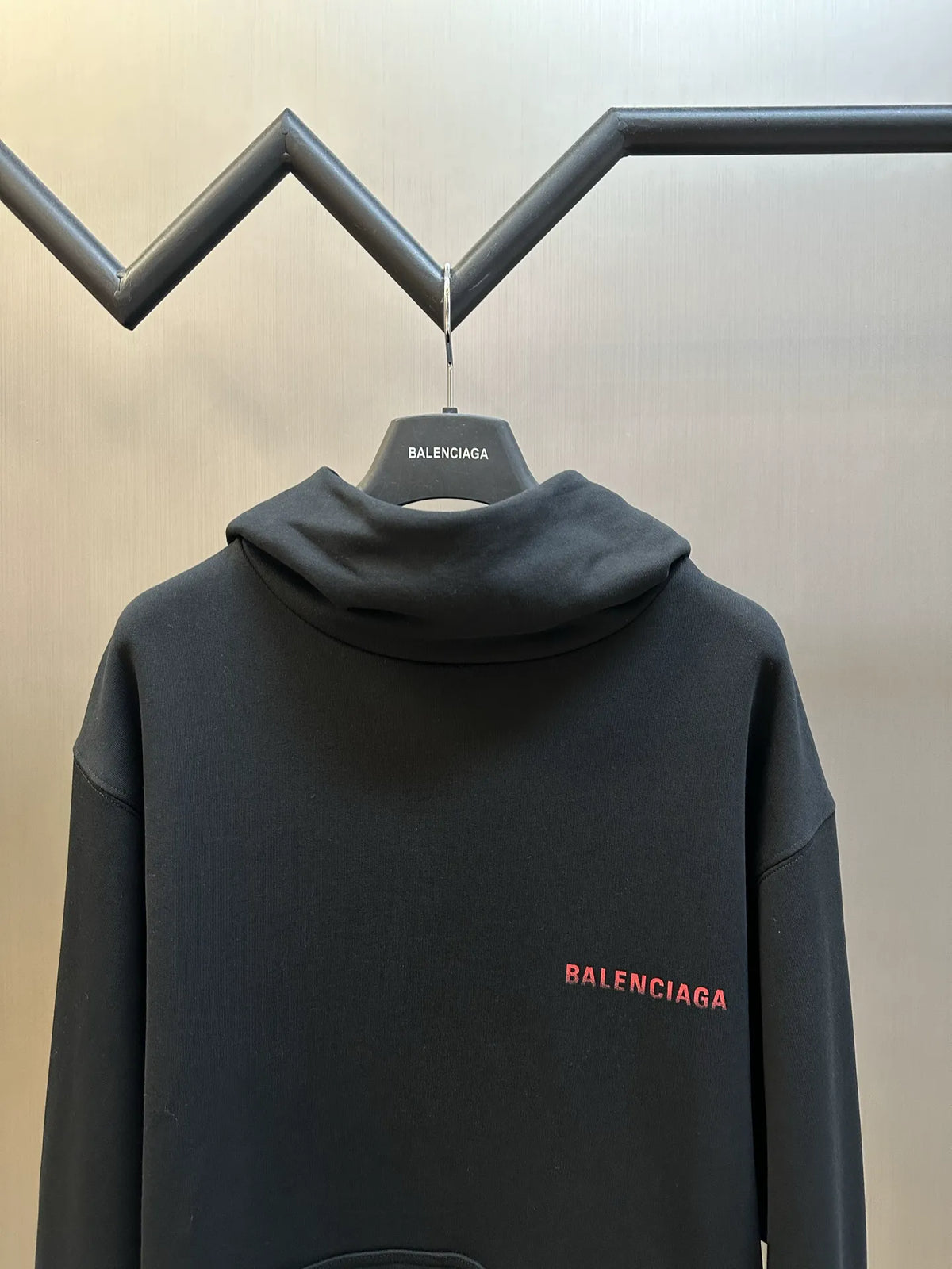 Black hoodie with hood and small red BALENCIAGA logo on chest