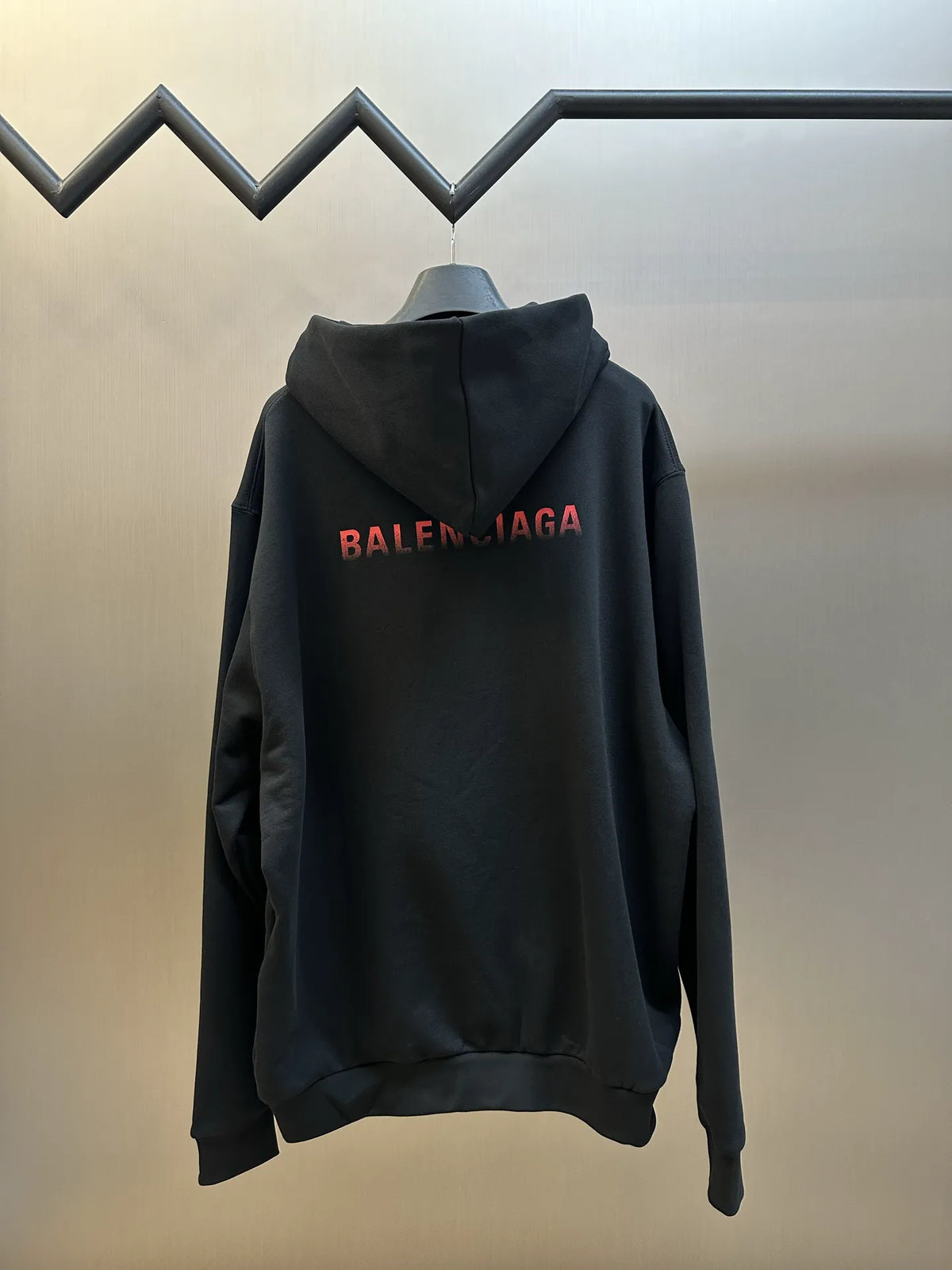 Black hoodie with hood and large red BALENCIAGA logo across chest