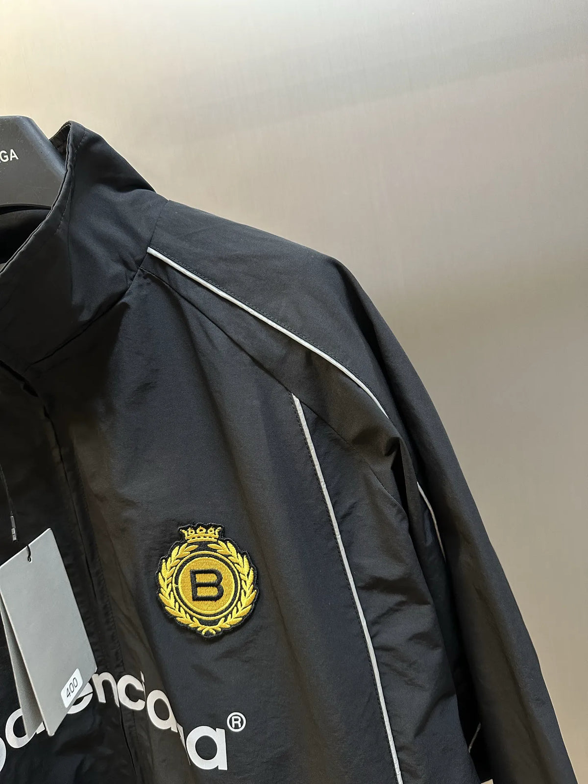 Balenciaga black windbreaker coat sleeve with gold B crest patch and white logo