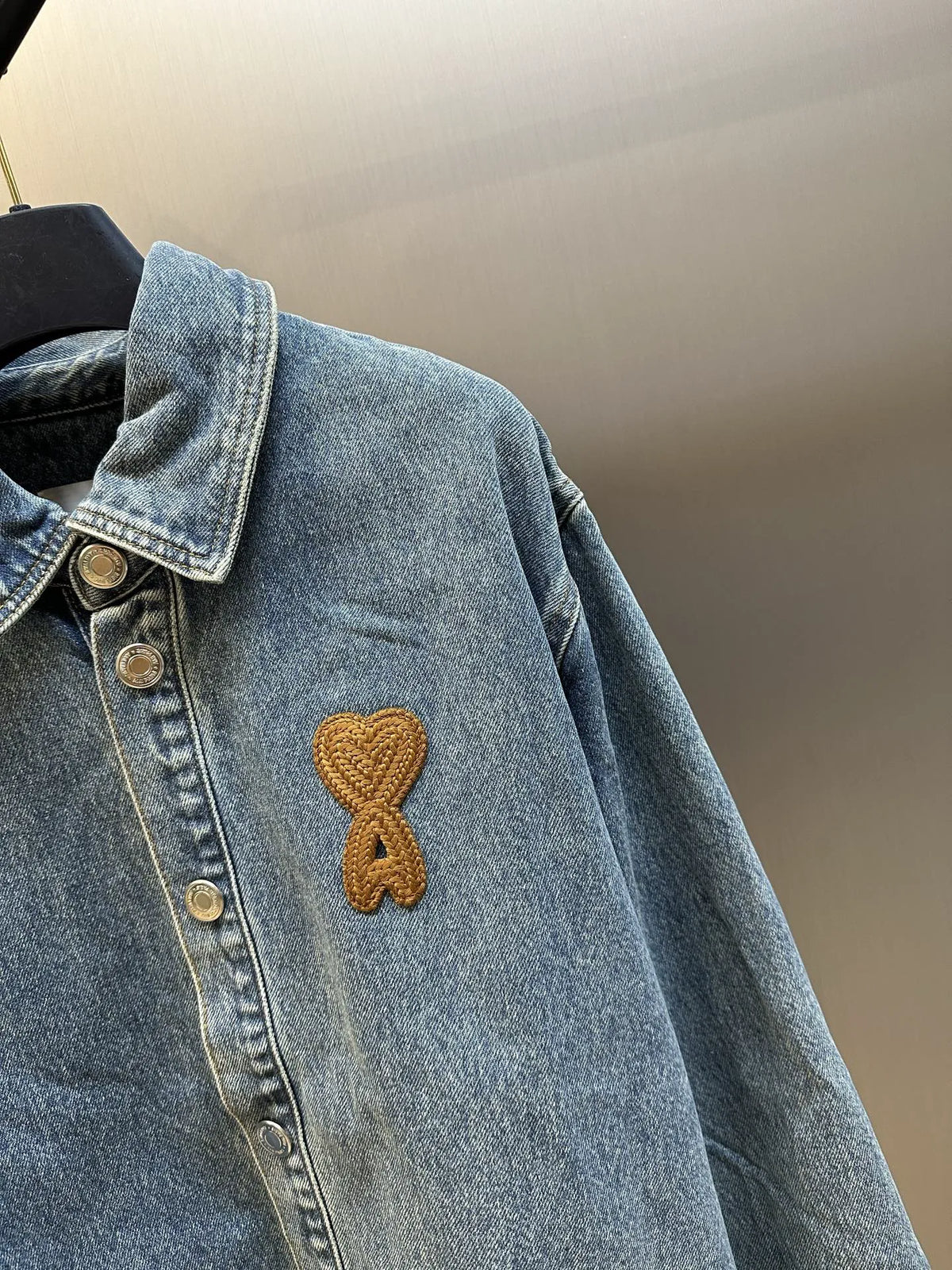 Amiri blue denim jacket sleeve with gold stitched ribbon logo
