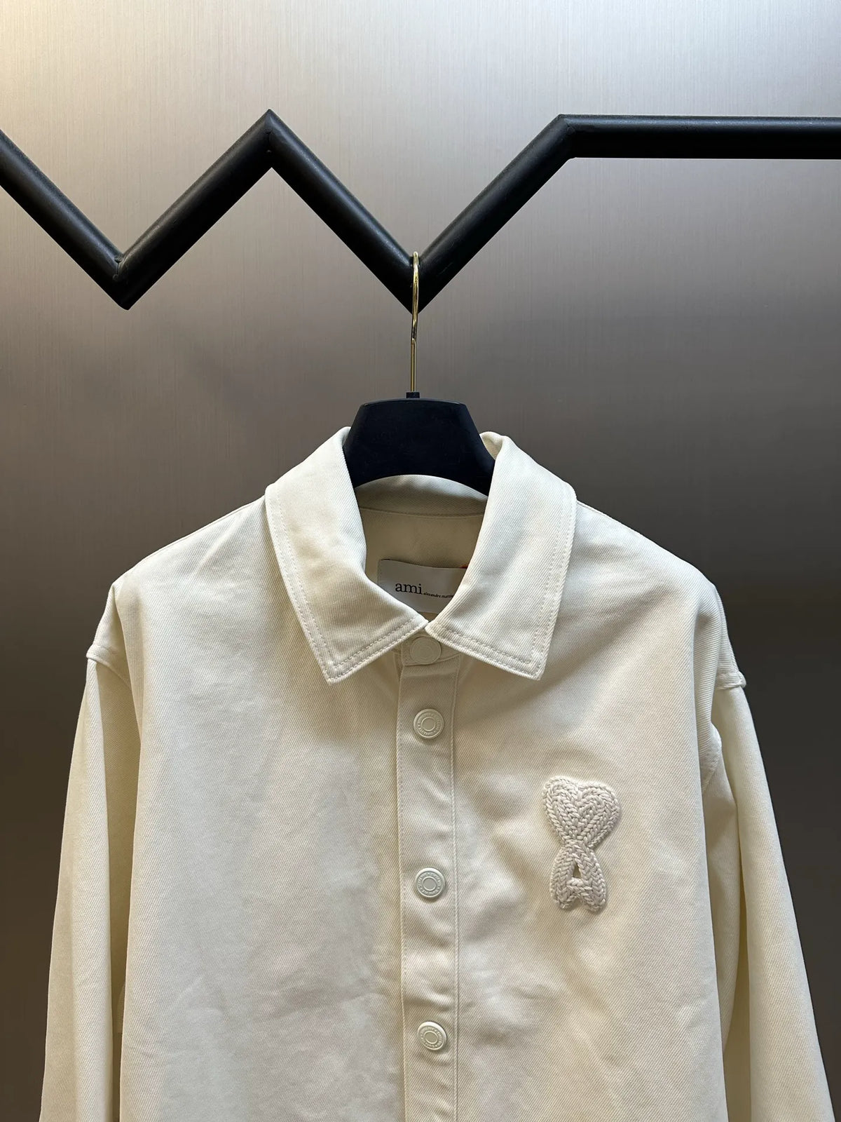 Cream long-sleeve button-up shirt, front view with collar and heart-shaped emblem