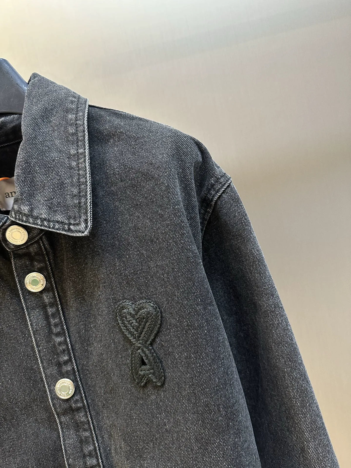Dark blue denim jacket sleeve with embroidered heart-style logo