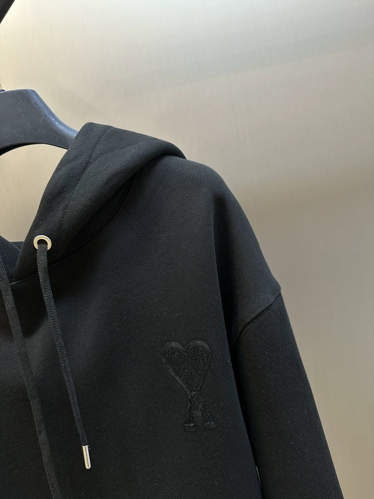 Black hoodie sleeve detail with subtle embossed chest logo