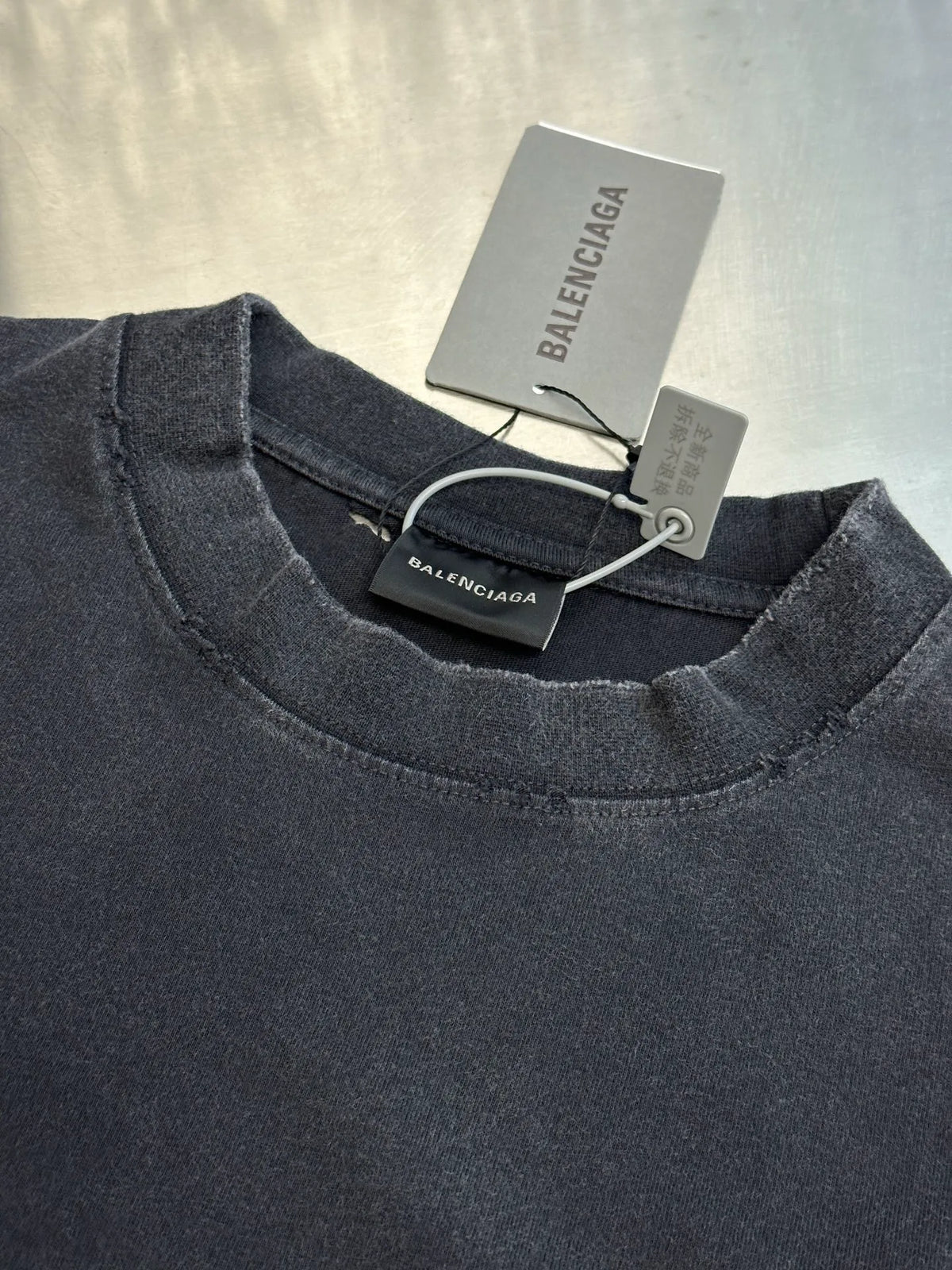 Charcoal crewneck sweatshirt neckline with Balenciaga logo label and hanging tags