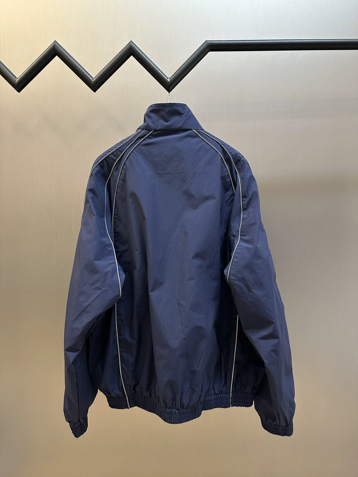 Navy back view zip-up jacket with stand collar and white track stripe seams