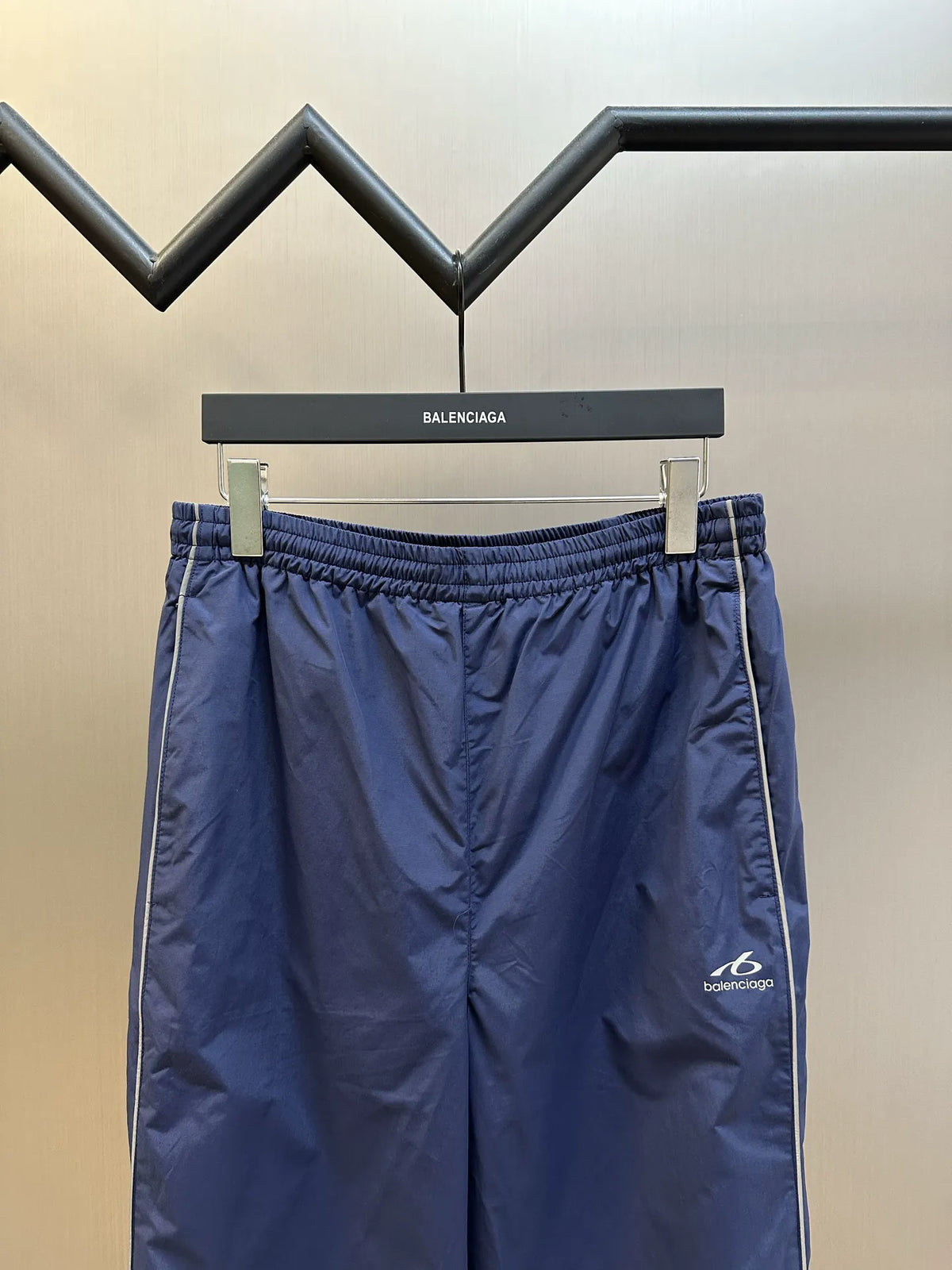 Navy Balenciaga pants on hanger, elastic waistband and side stripe detail