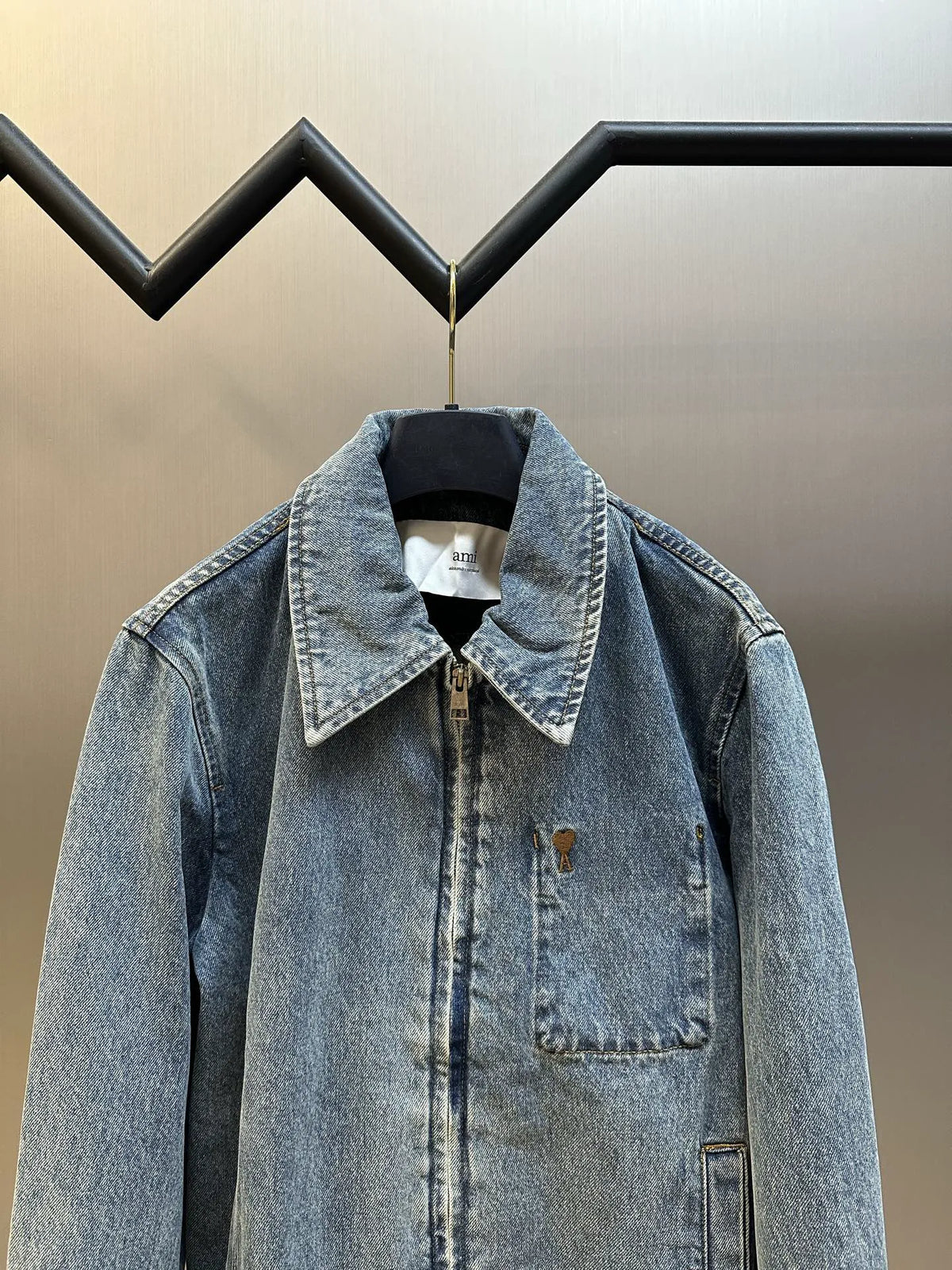 Light wash denim jacket on hanger with pointed collar and single chest patch pocket