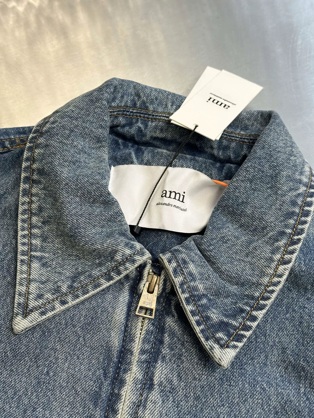 Light wash denim jacket with contrast beige neck tag and front snap placket