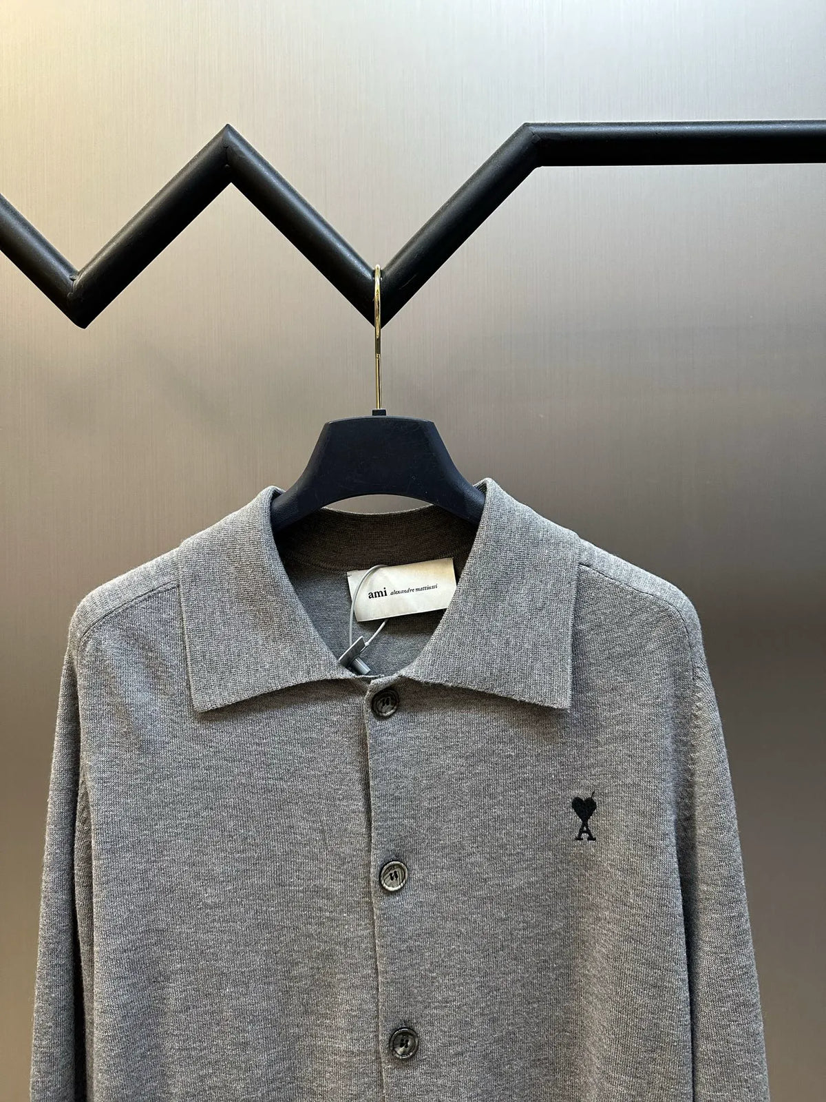 Gray knit long-sleeve polo with pointed collar, four buttons, and black A logo