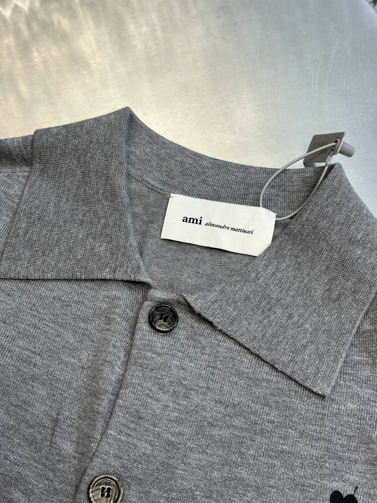Gray knit polo with pointed collar, button front, and ami neck label