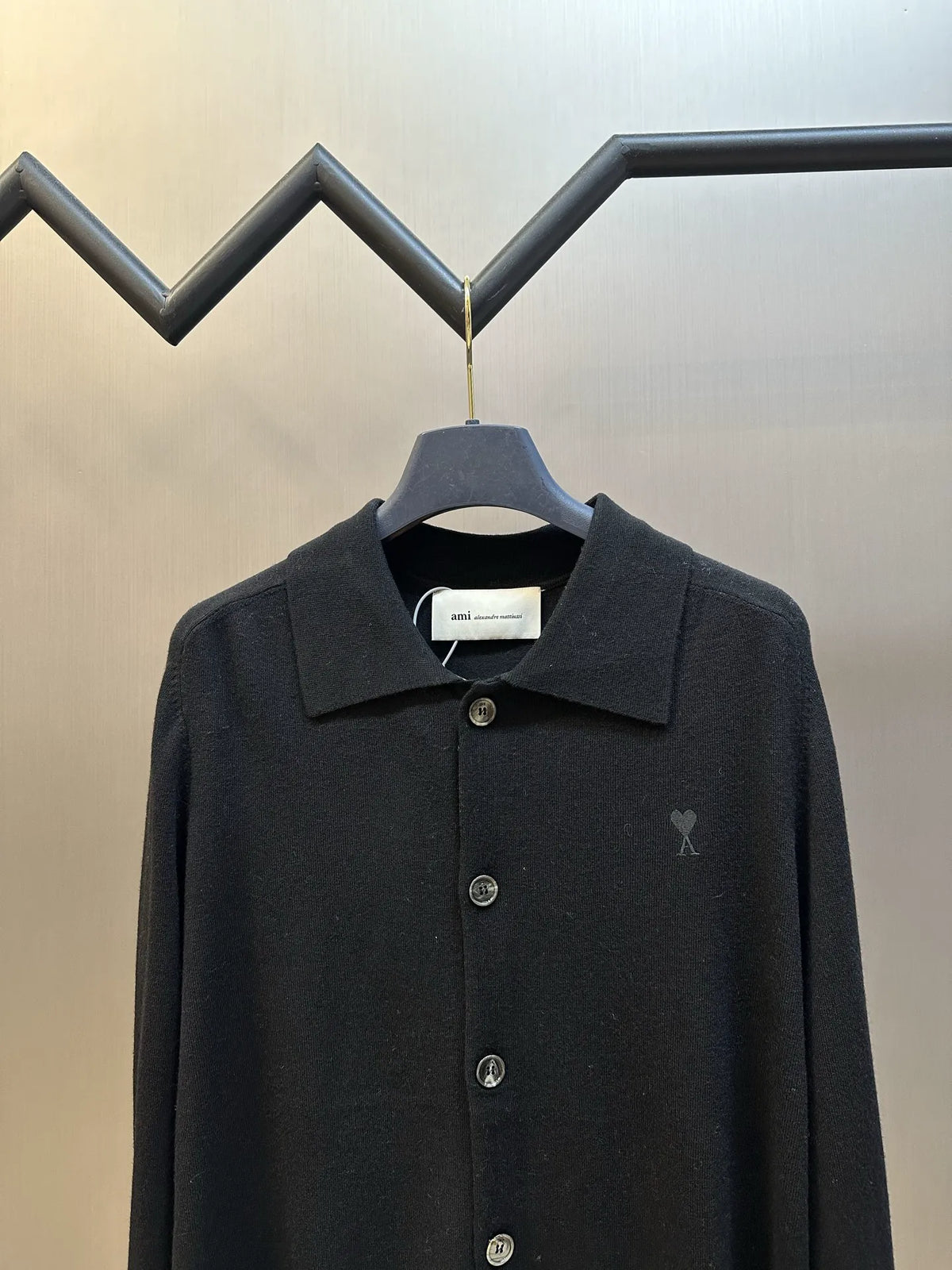Amiri black coat with pointed collar, front button placket, and small chest logo