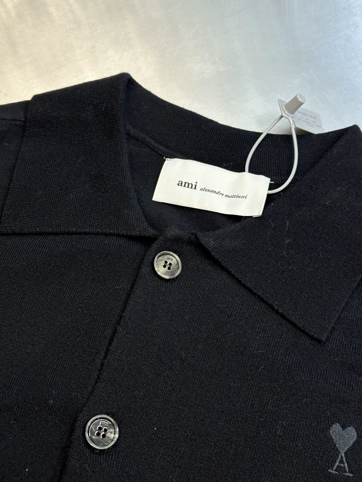 Amiri black coat with pointed collar, metal buttons, and small heart-and-A logo