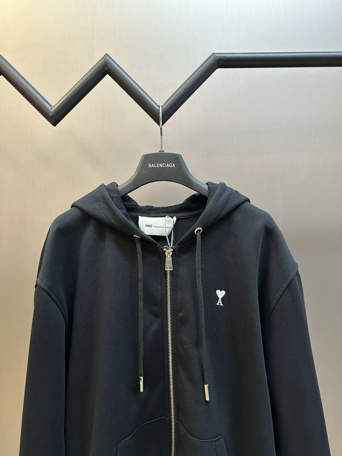 Black zip-up hoodie with hood, drawstrings, and small chest logo