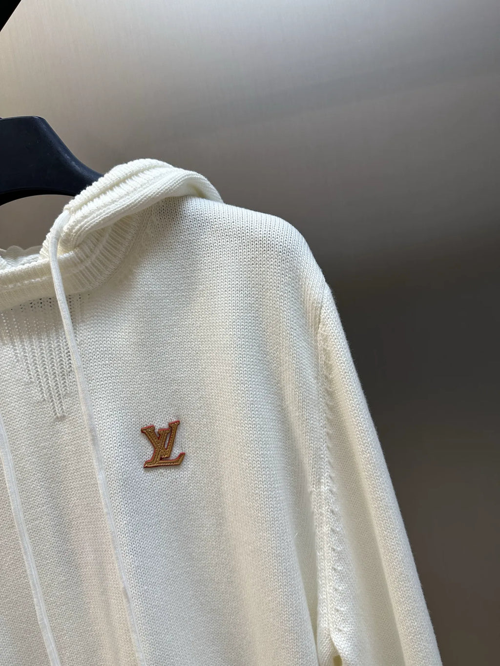 Cream hoodie with hood and small brown LV logo, close view of the shoulder area