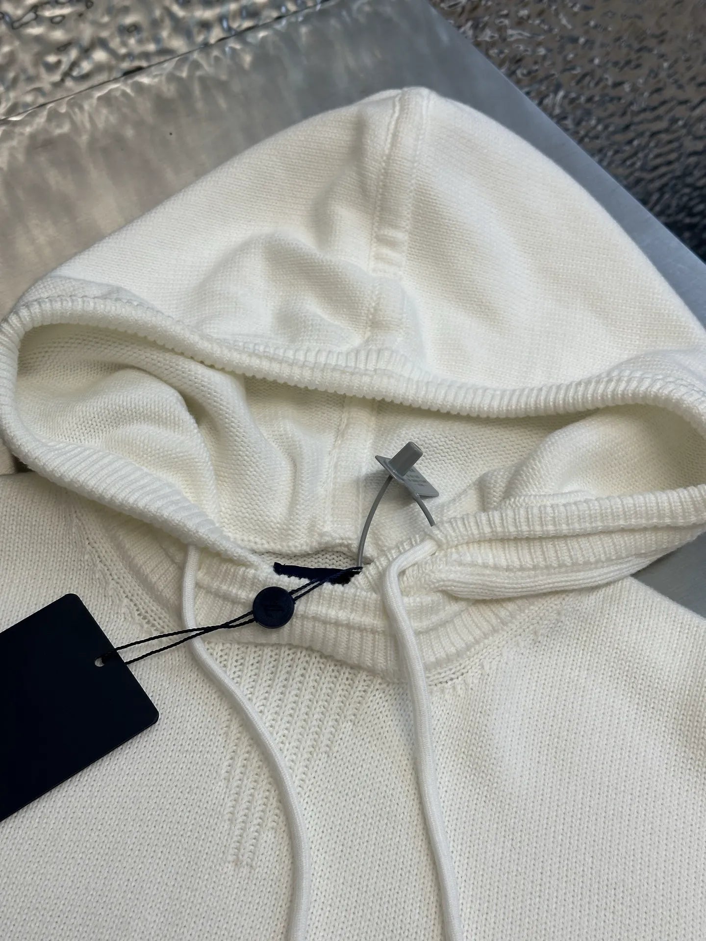 Cream knit hoodie with drawstring hood and interior black tag