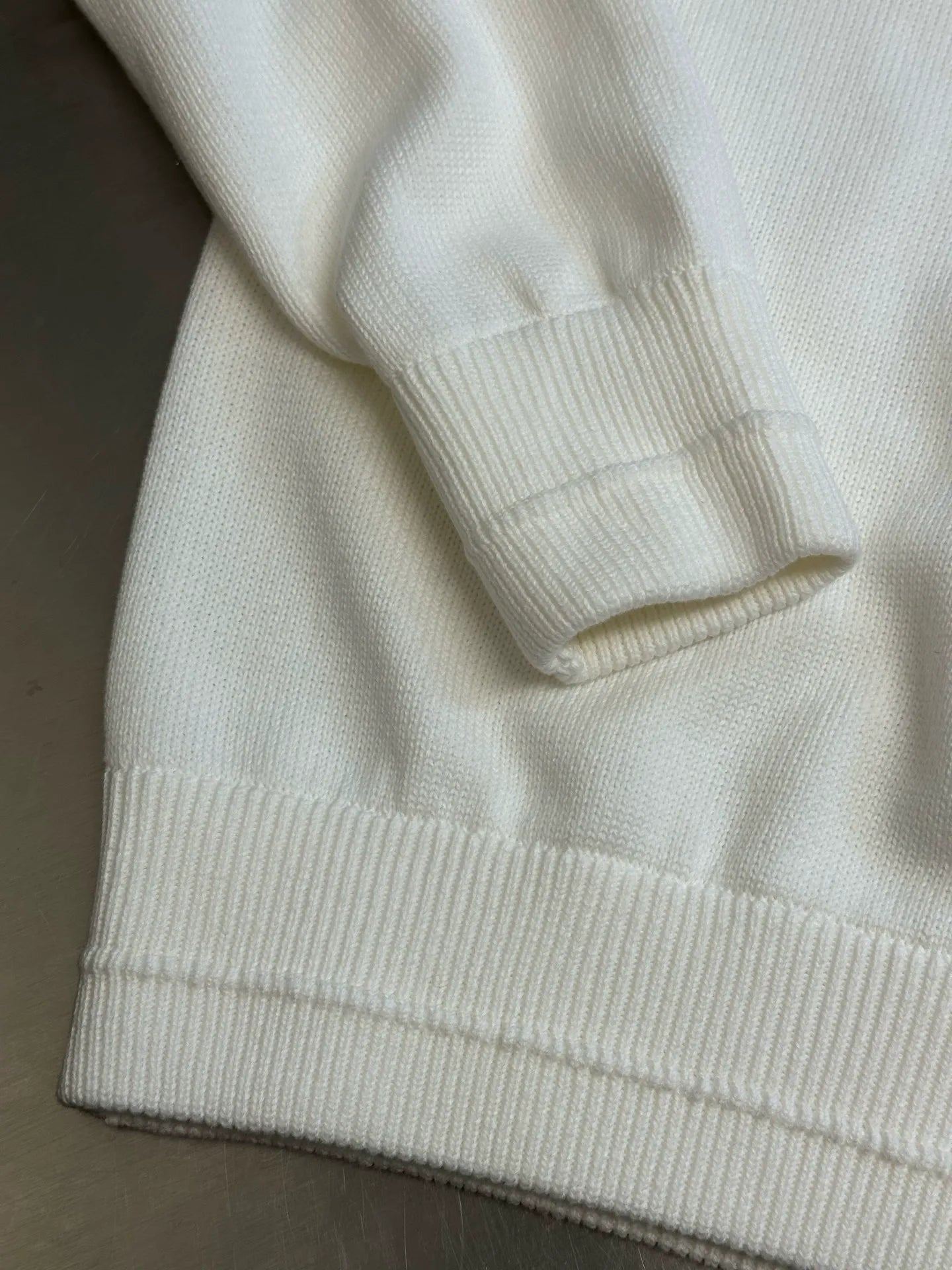 Cream hoodie with ribbed hem and sleeve cuffs visible in close-up
