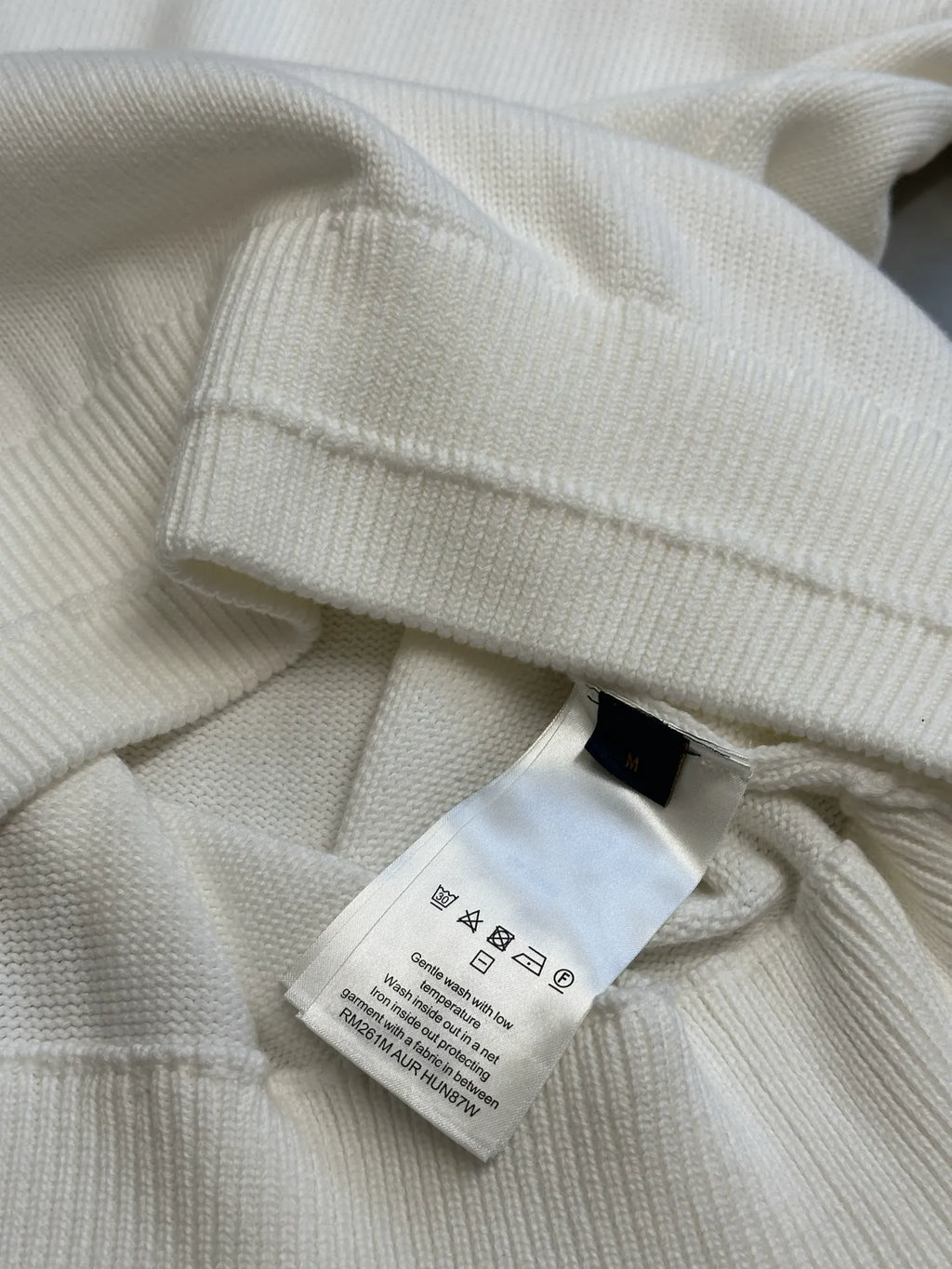 Cream hoodie neckline close-up with interior care label tag
