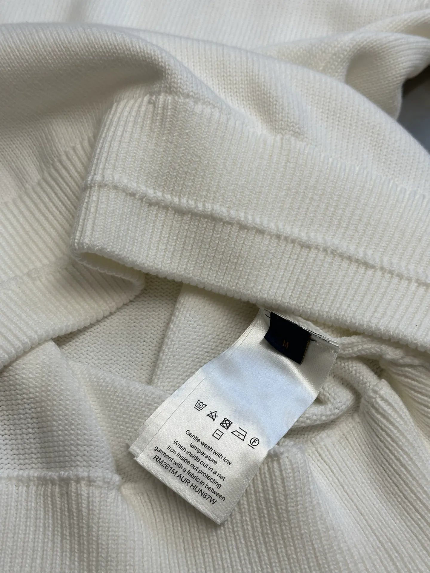 Cream hoodie neckline close-up with interior care label tag