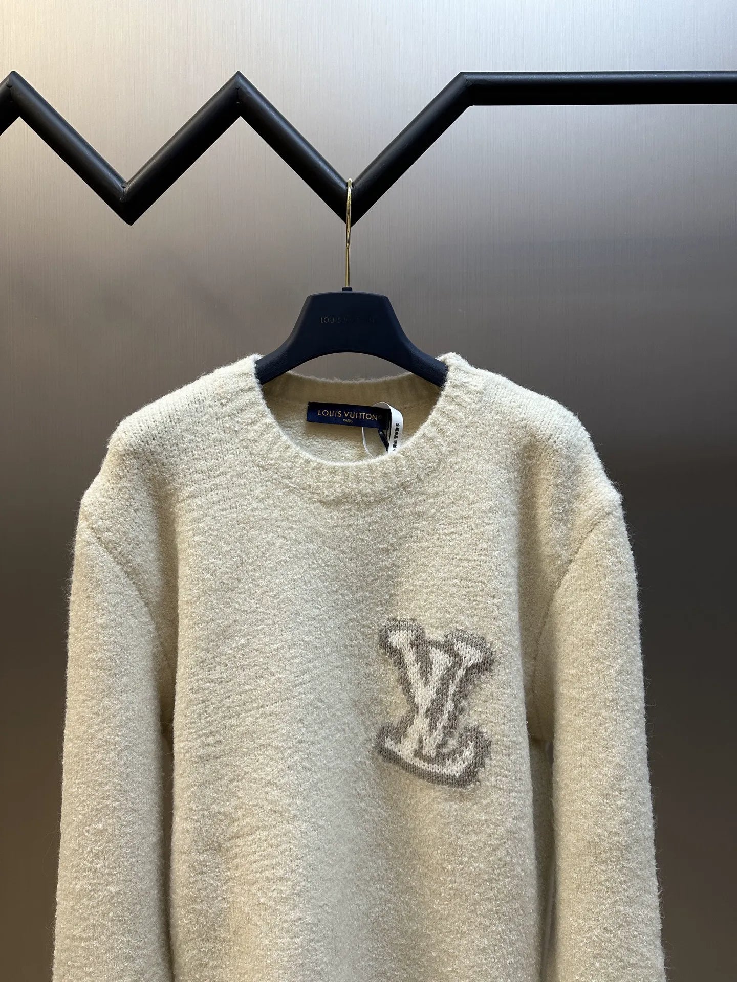 Off-white long-sleeve crewneck sweater with dark LV-style logo at center front