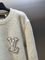 Off-white knit sweater close-up showing LV-style monogram and ribbed sleeve edge