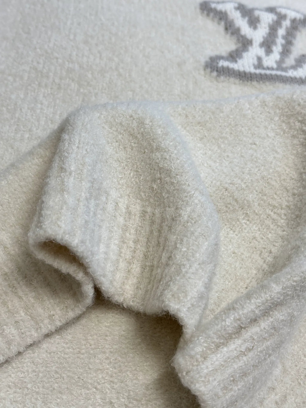 Off-white knit sweater with ribbed cuffs and visible sleeve seam detail