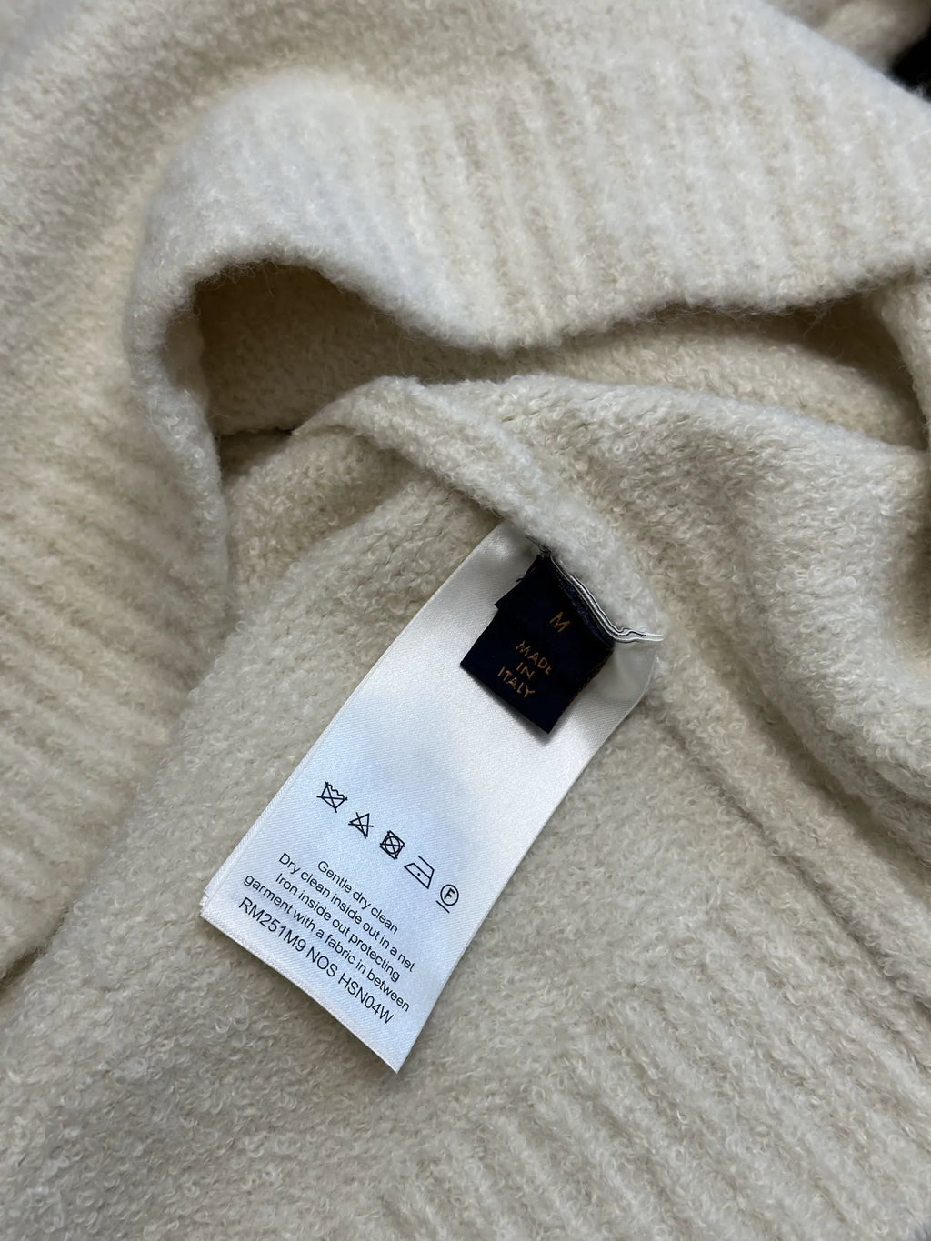 Off-white knit sweater with interior care label and blue logo tag