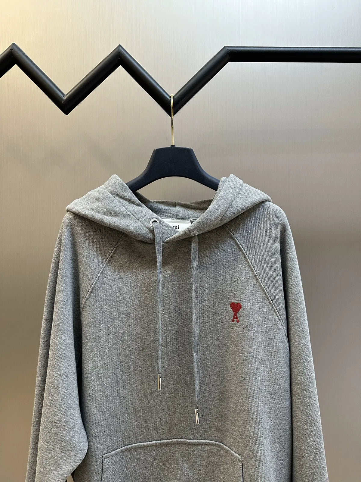 Heather gray pullover hoodie on hanger with drawstring hood and small red logo on chest
