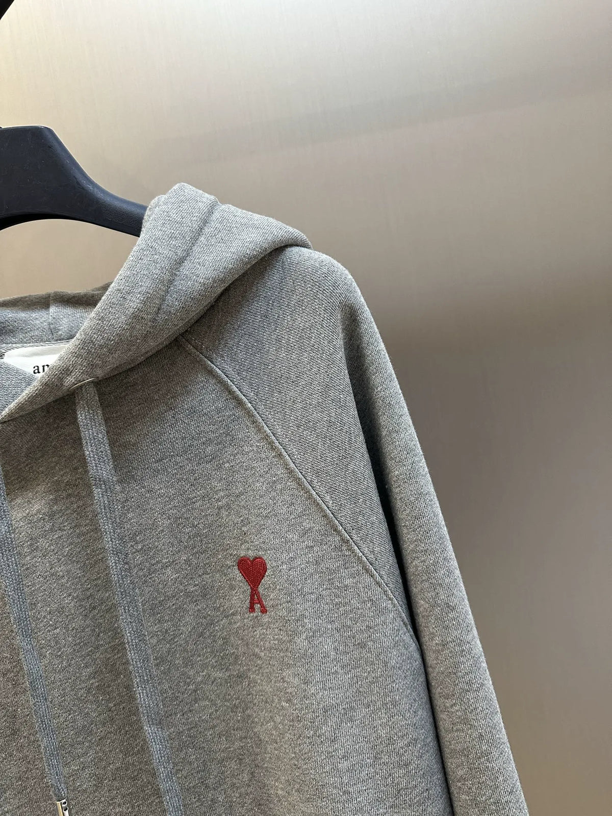 Heather gray hoodie sleeve and chest area with small red logo patch