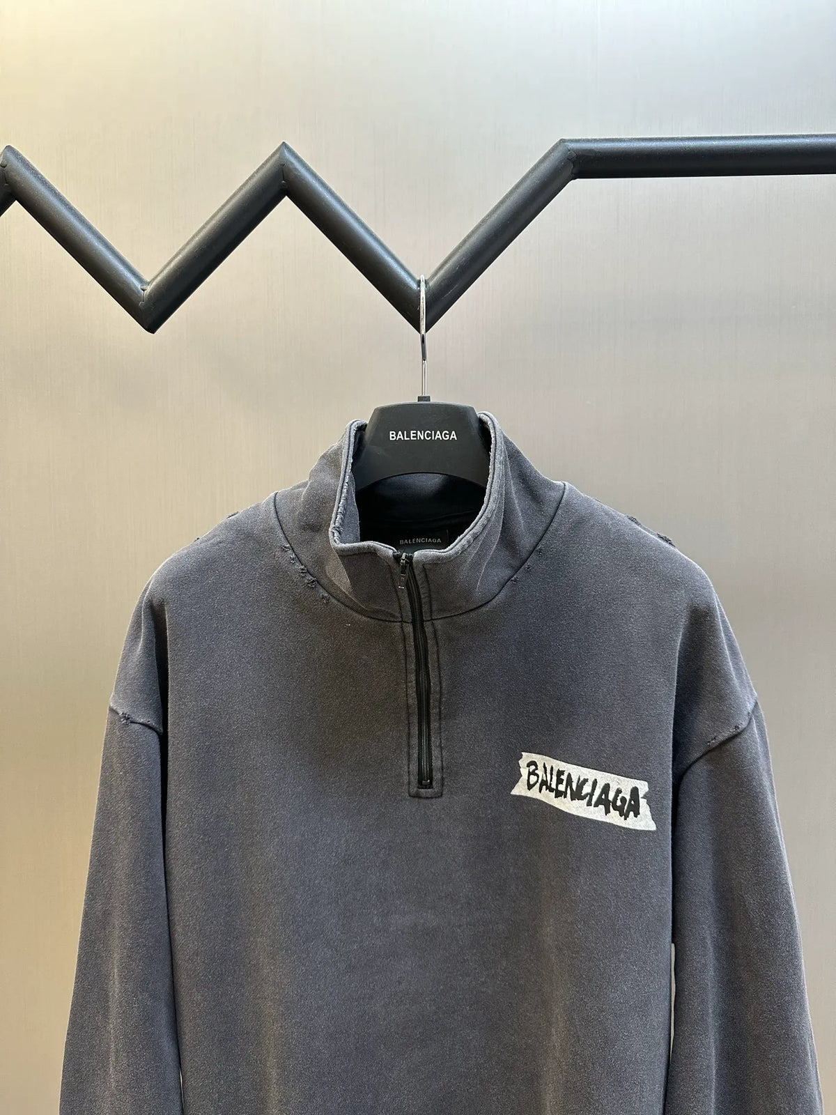 Balenciaga dark gray quarter-zip sweatshirt on hanger, logo patch at chest