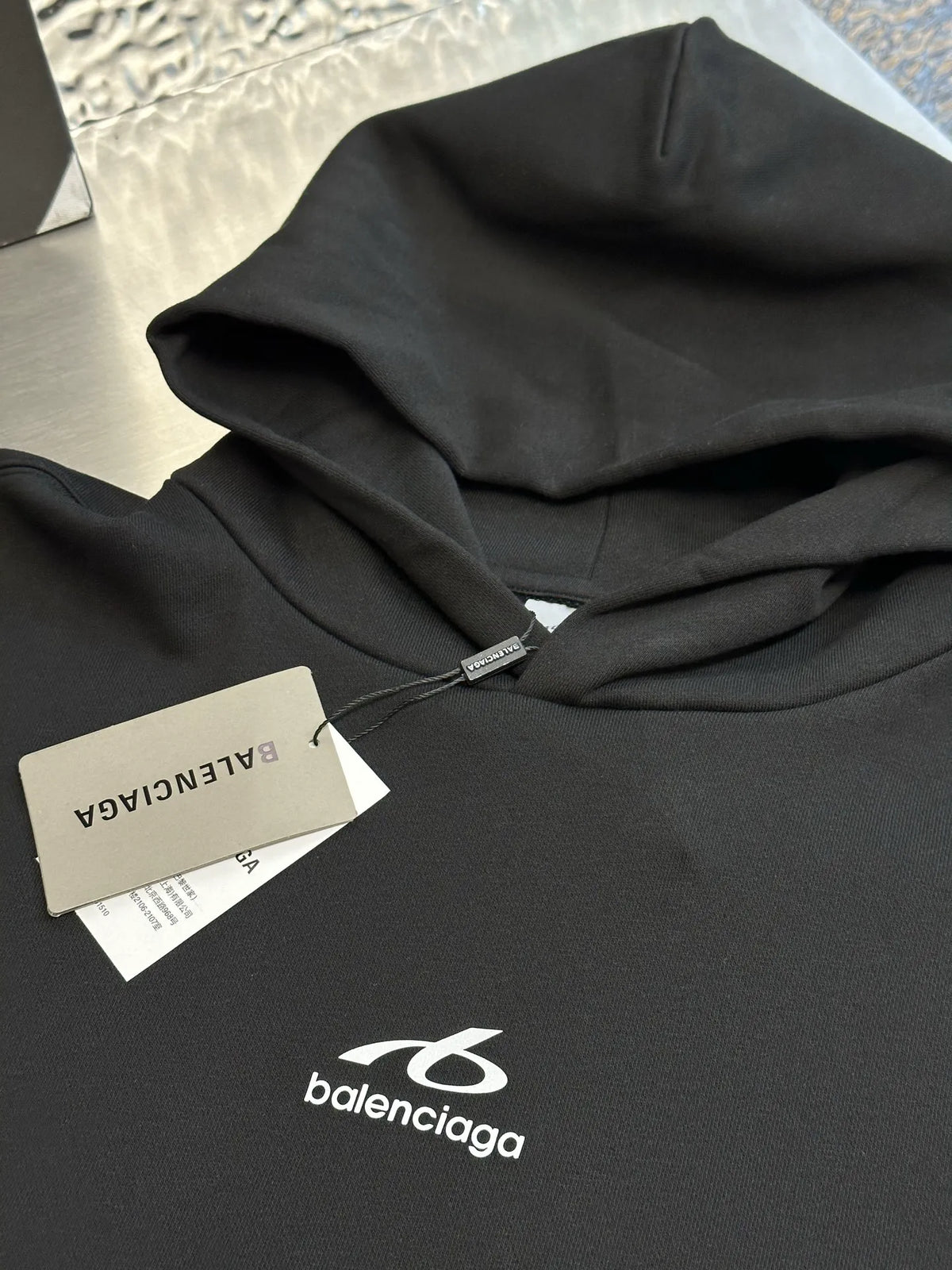 Black Balenciaga hoodie fabric close-up with hood folds and logo