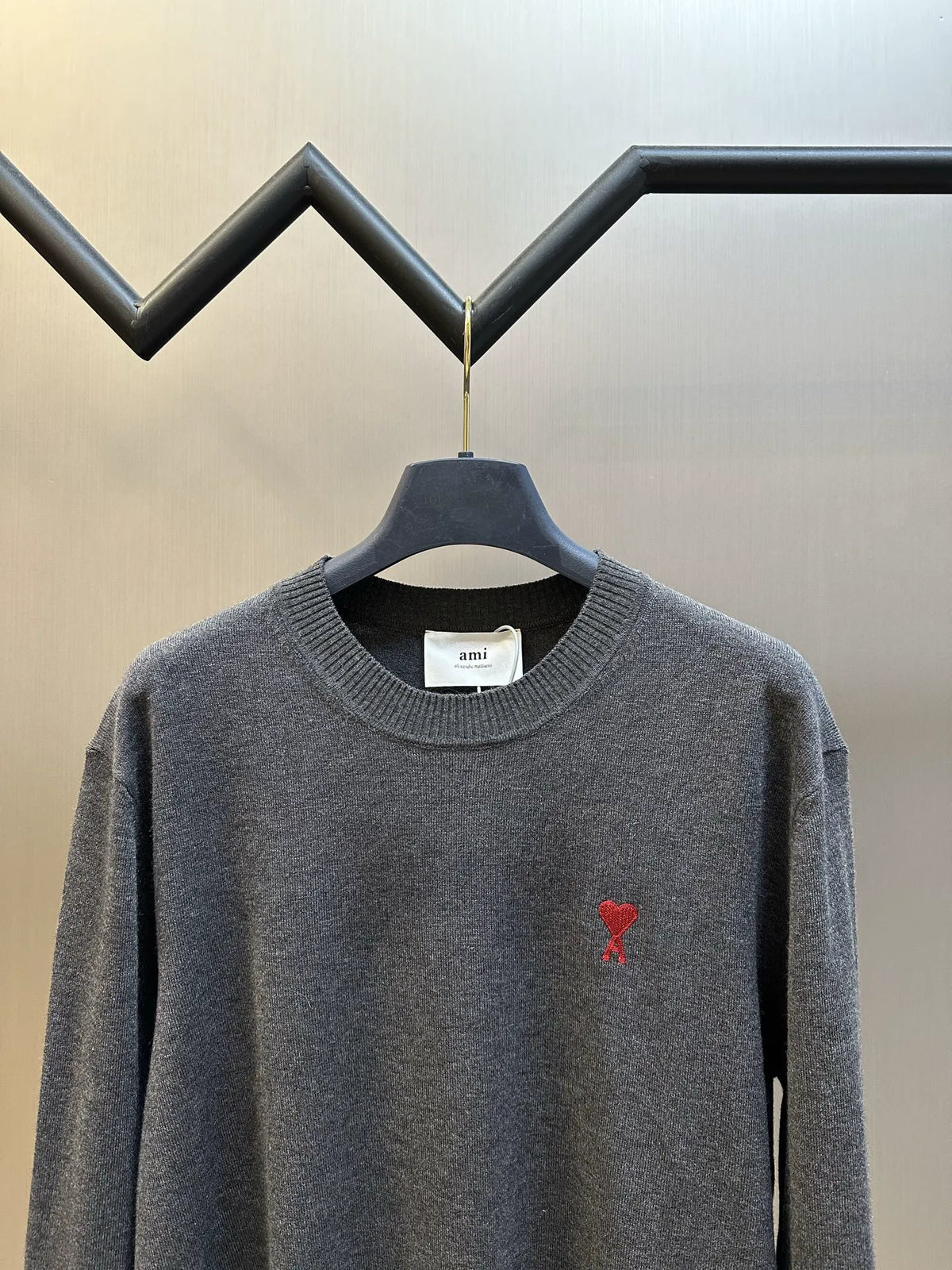 Dark gray crewneck knit sweater, red heart-style graphic at left chest