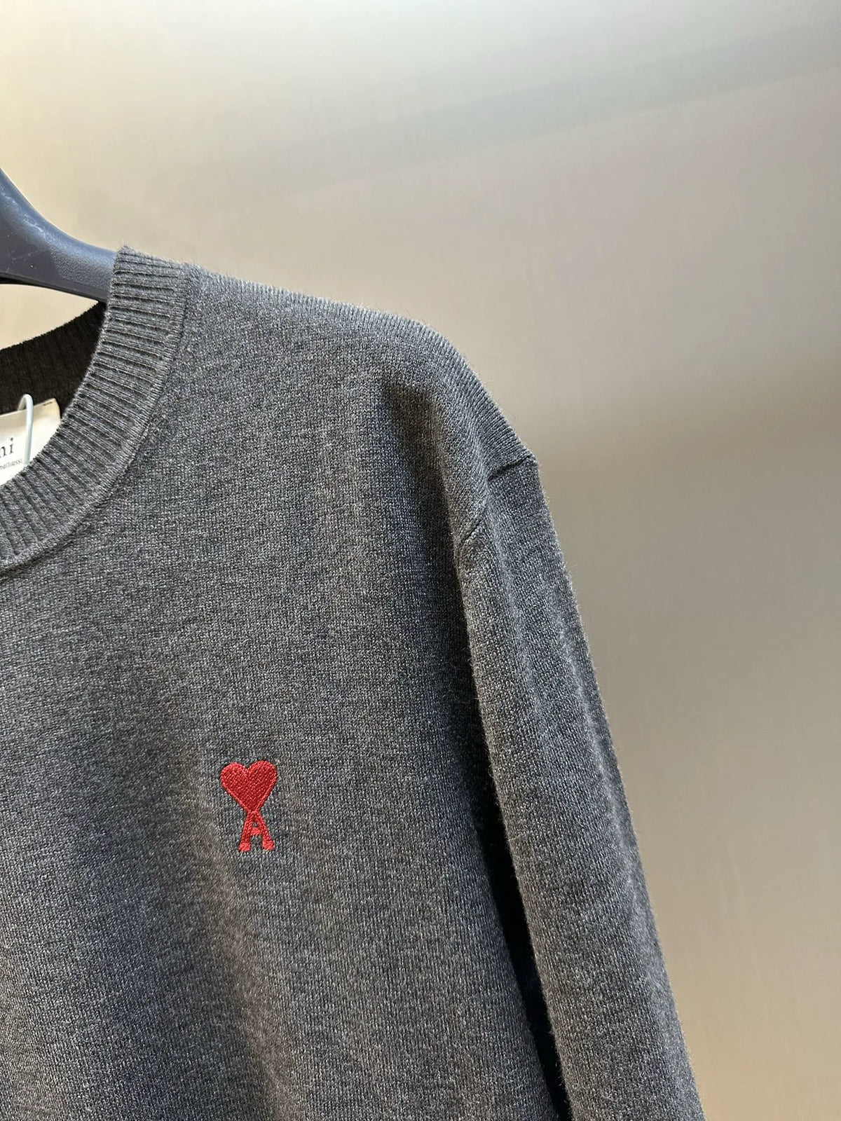Dark gray knit sweater sleeve with red heart emblem on the front