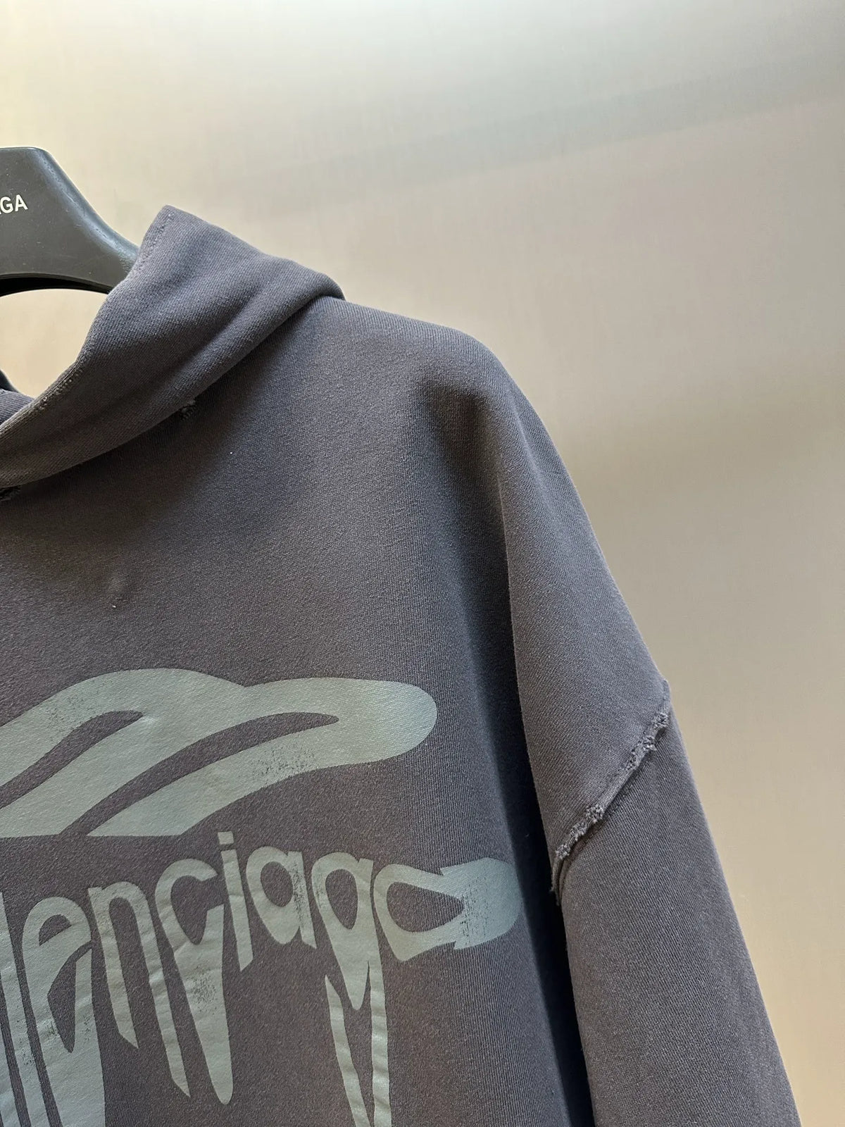 Balenciaga hoodie sweatshirt close-up of faded chest logo print on dark gray fabric