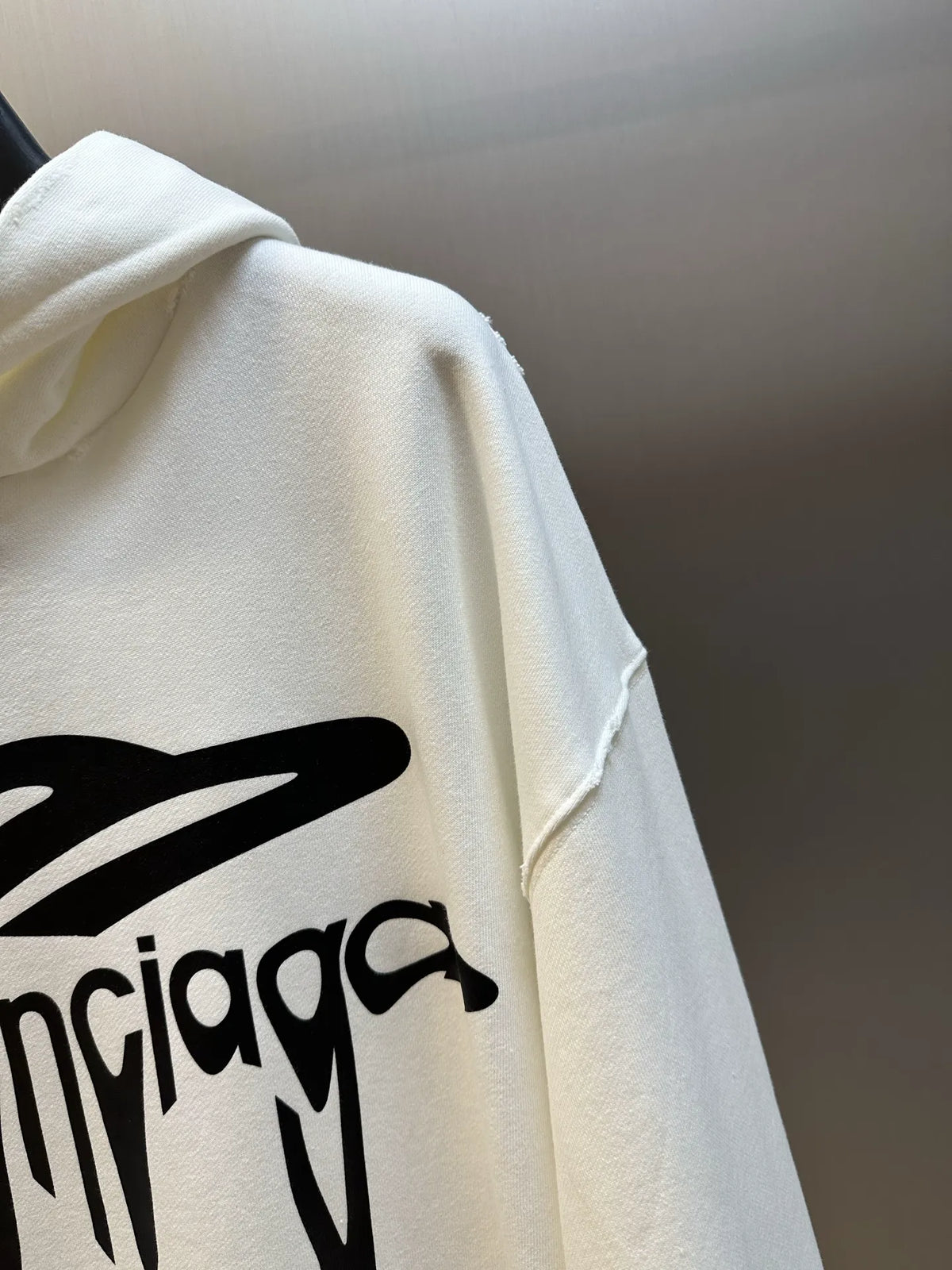 White hoodie sleeve with large black logo graphic print