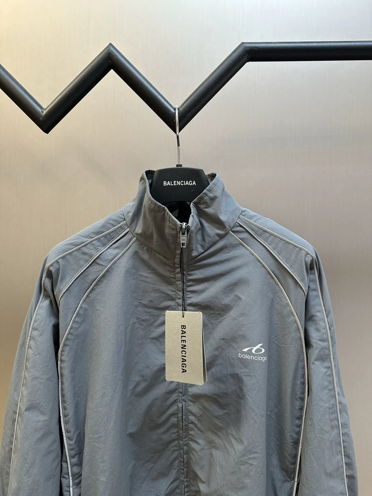 Light blue-gray zip-up jacket front view with stand collar and interior tag
