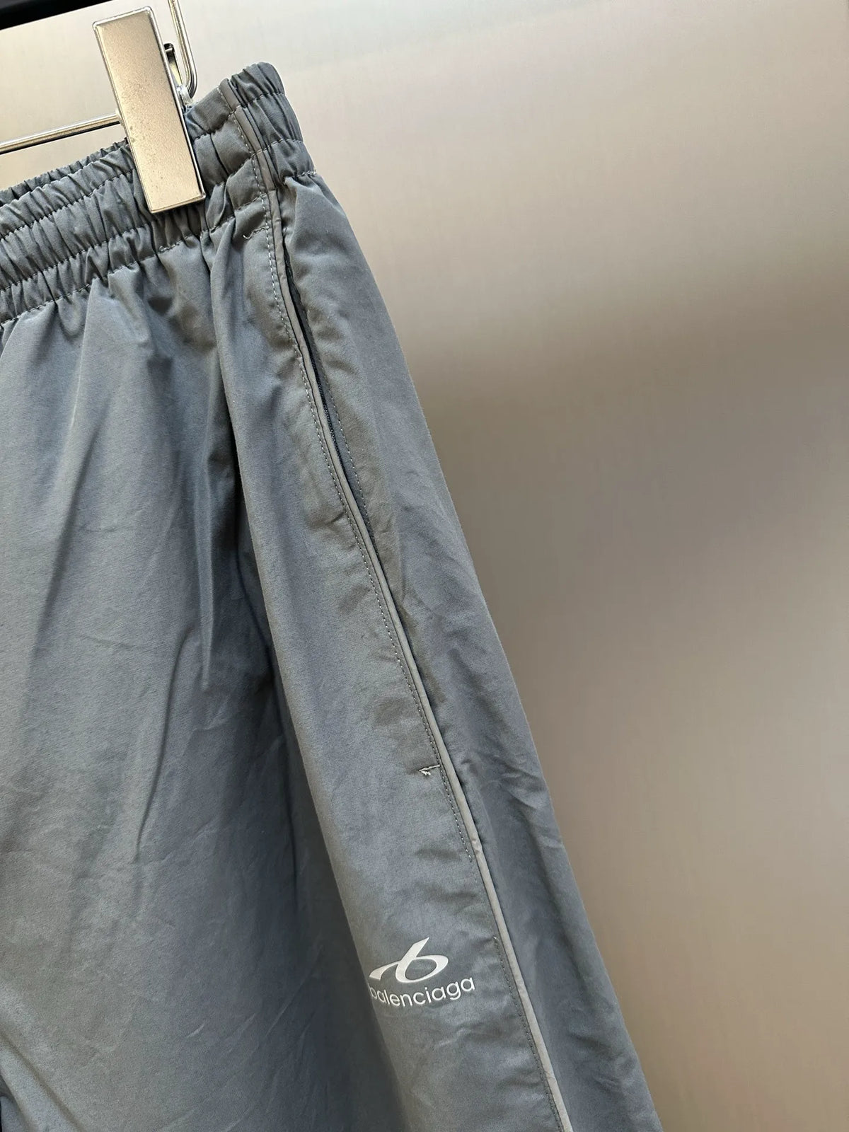 Light gray Balenciaga pants close-up of side seam zipper and relaxed fabric