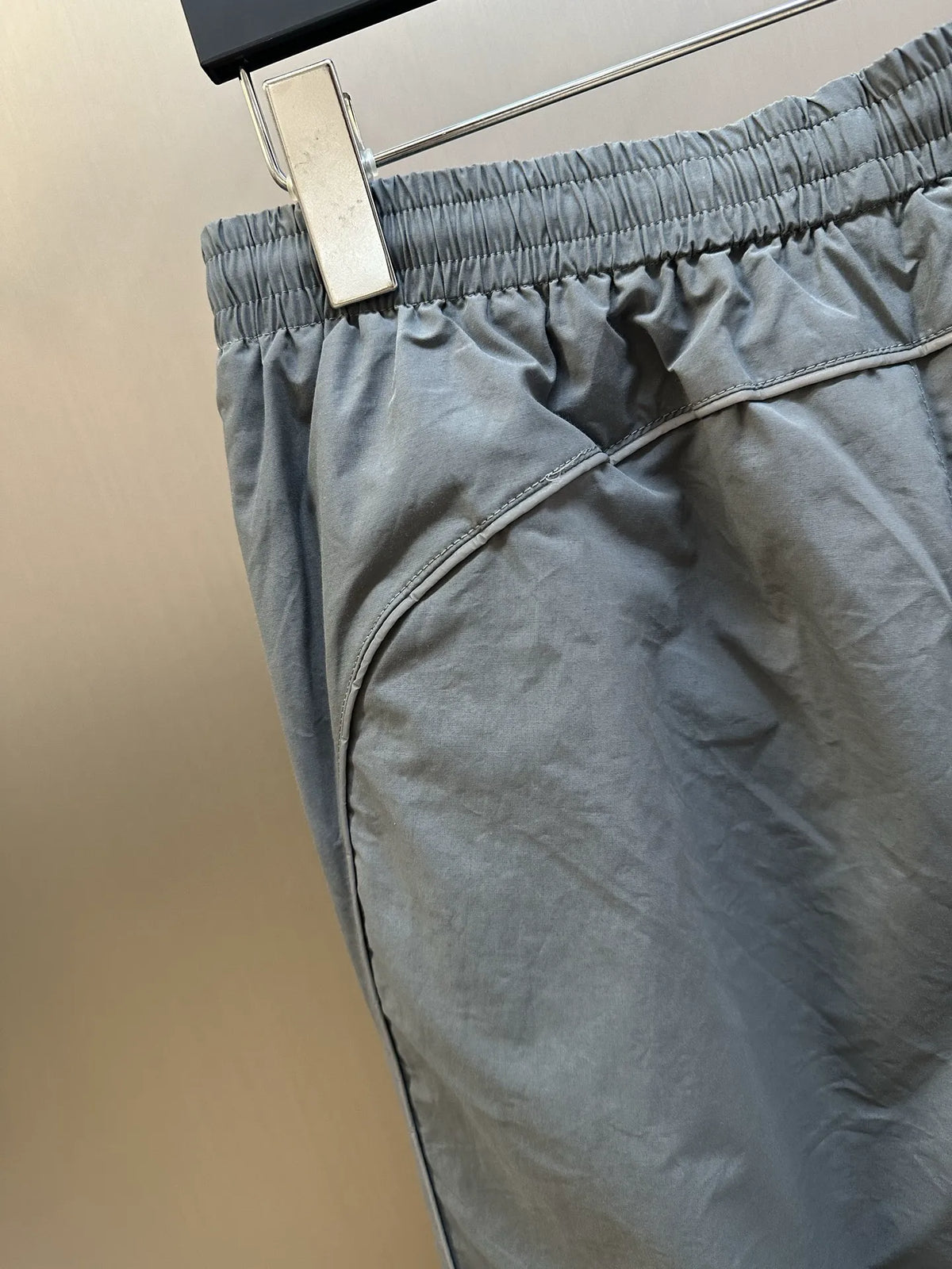 Light gray Balenciaga pants close-up of elastic waistband and curved zipper fly