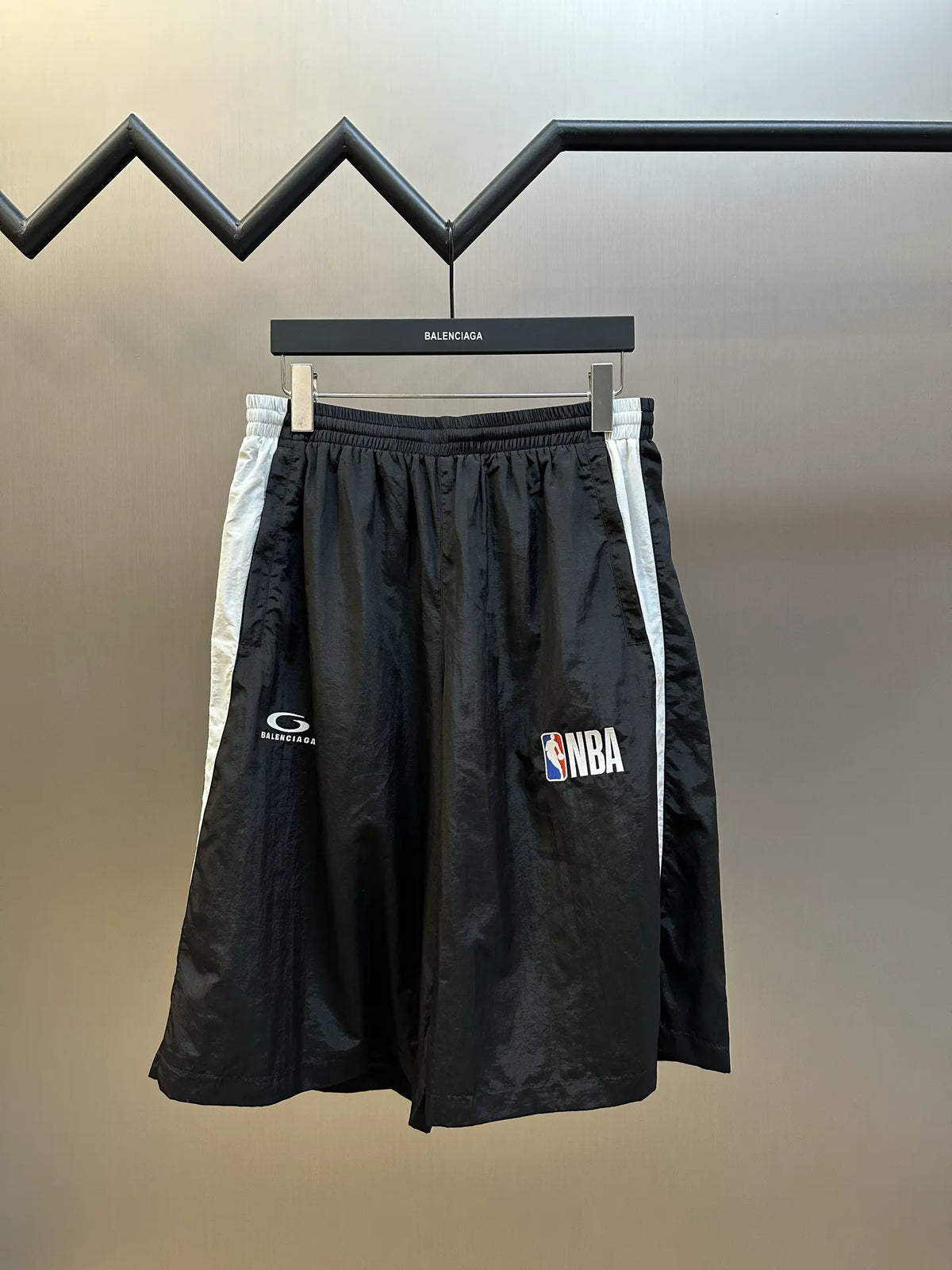 Balenciaga black shorts with elastic waistband, white side stripe, and NBA side patch