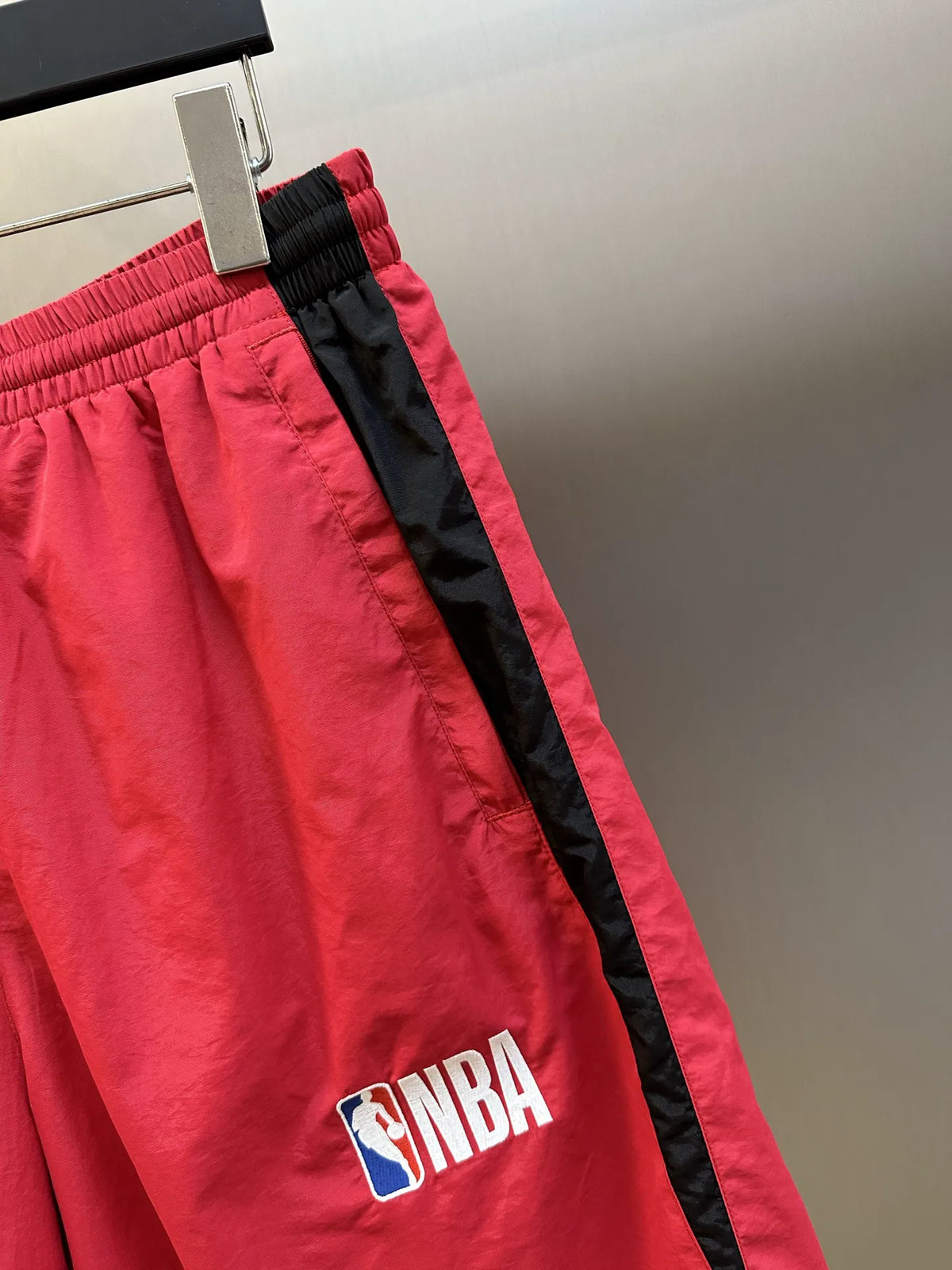 Balenciaga red basketball shorts detail with black side stripe and NBA logo patch