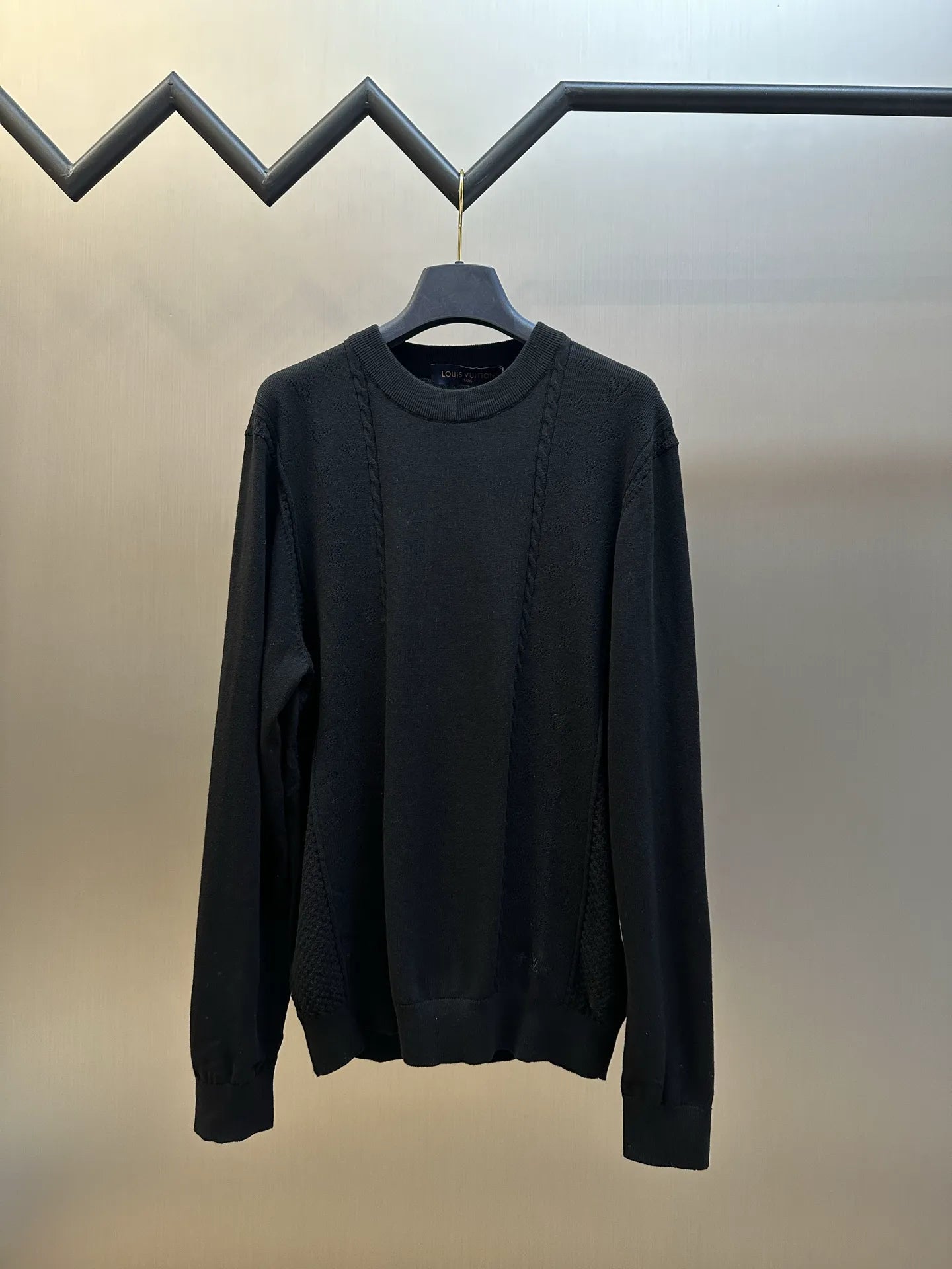 Black long-sleeve sweater on hanger with crew neck and ribbed cuffs