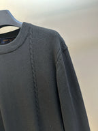 Black long-sleeve sweater with braided cable detail along the shoulder