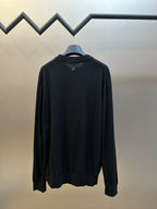 Black long-sleeve sweater on hanger with crew neck and ribbed hem